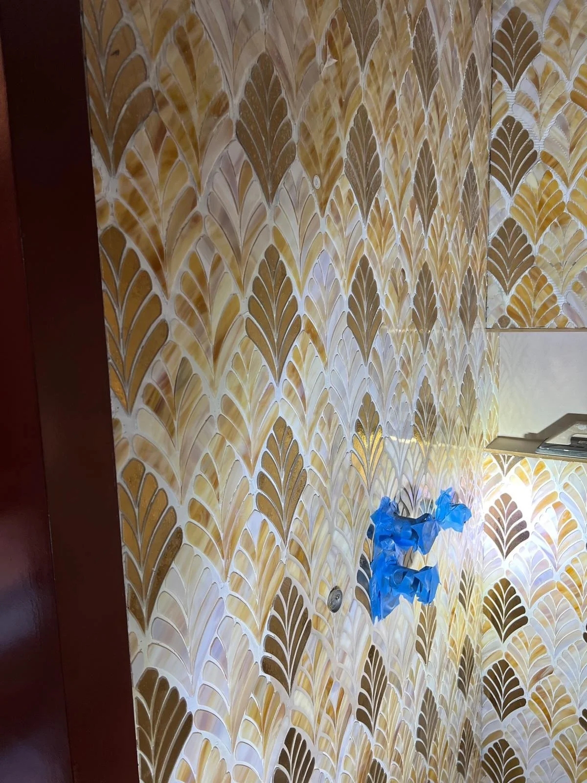 Interior wall with a yellow and brown decorative pattern, partially covered by blue painter's tape.