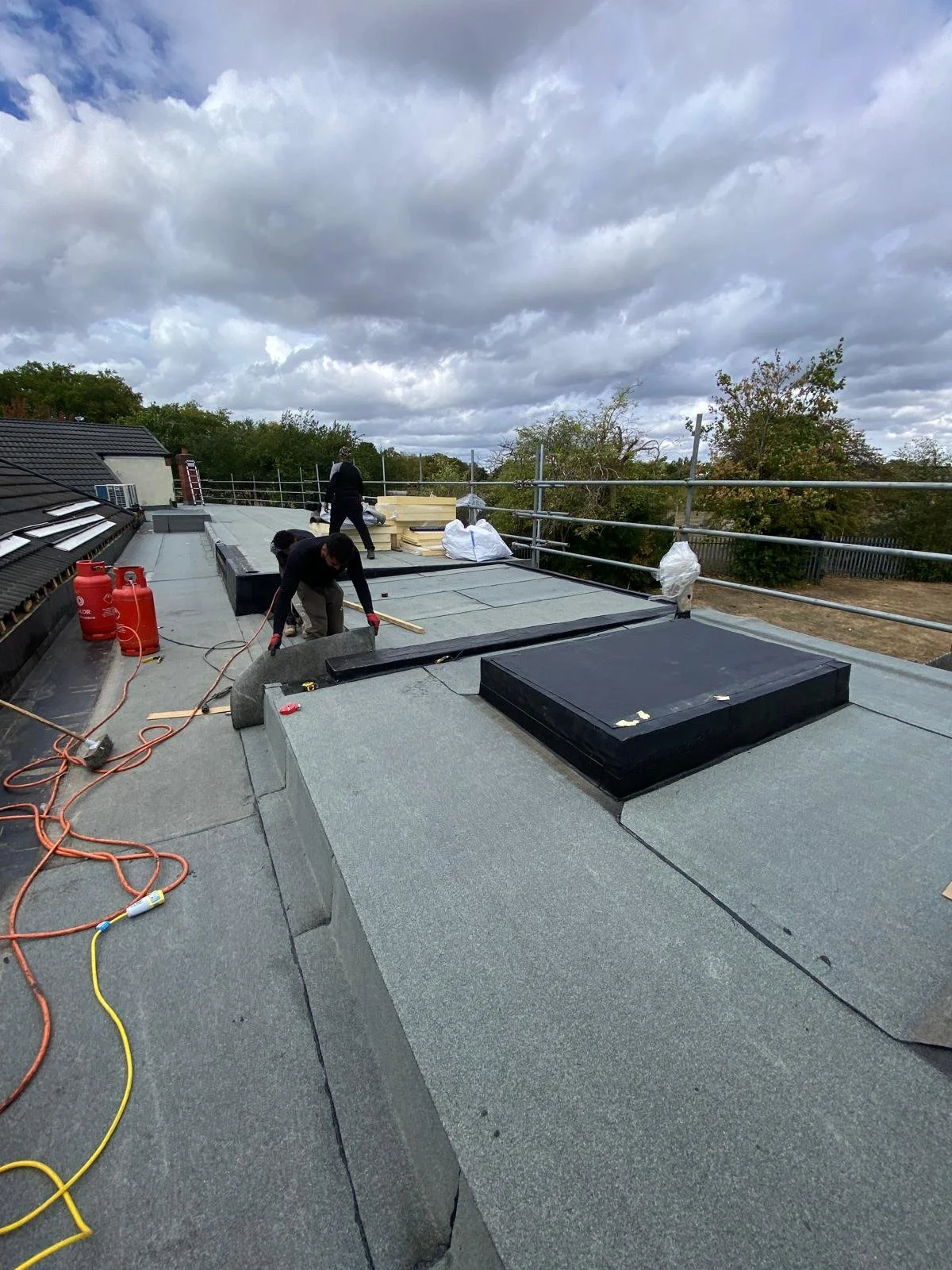 Workers installing a new roof on a building during cloudy weather.