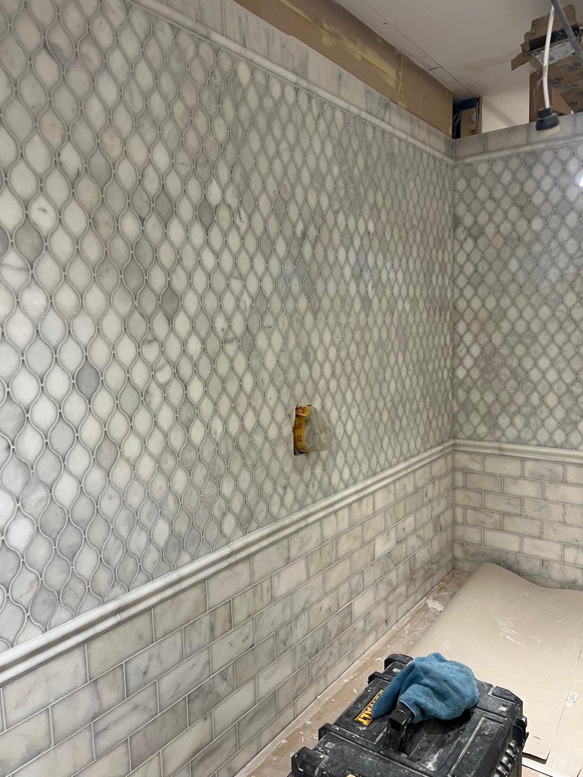 Interior view of a room under construction with decorative marble wall tiles, wainscoting, and electrical outlets.