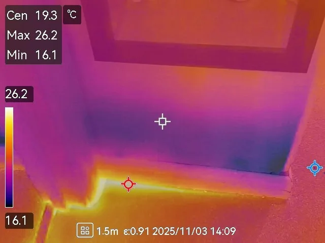 Thermal image of the base of a refrigerator showing heat variation, with higher temperatures near the bottom and cooler areas at the top.