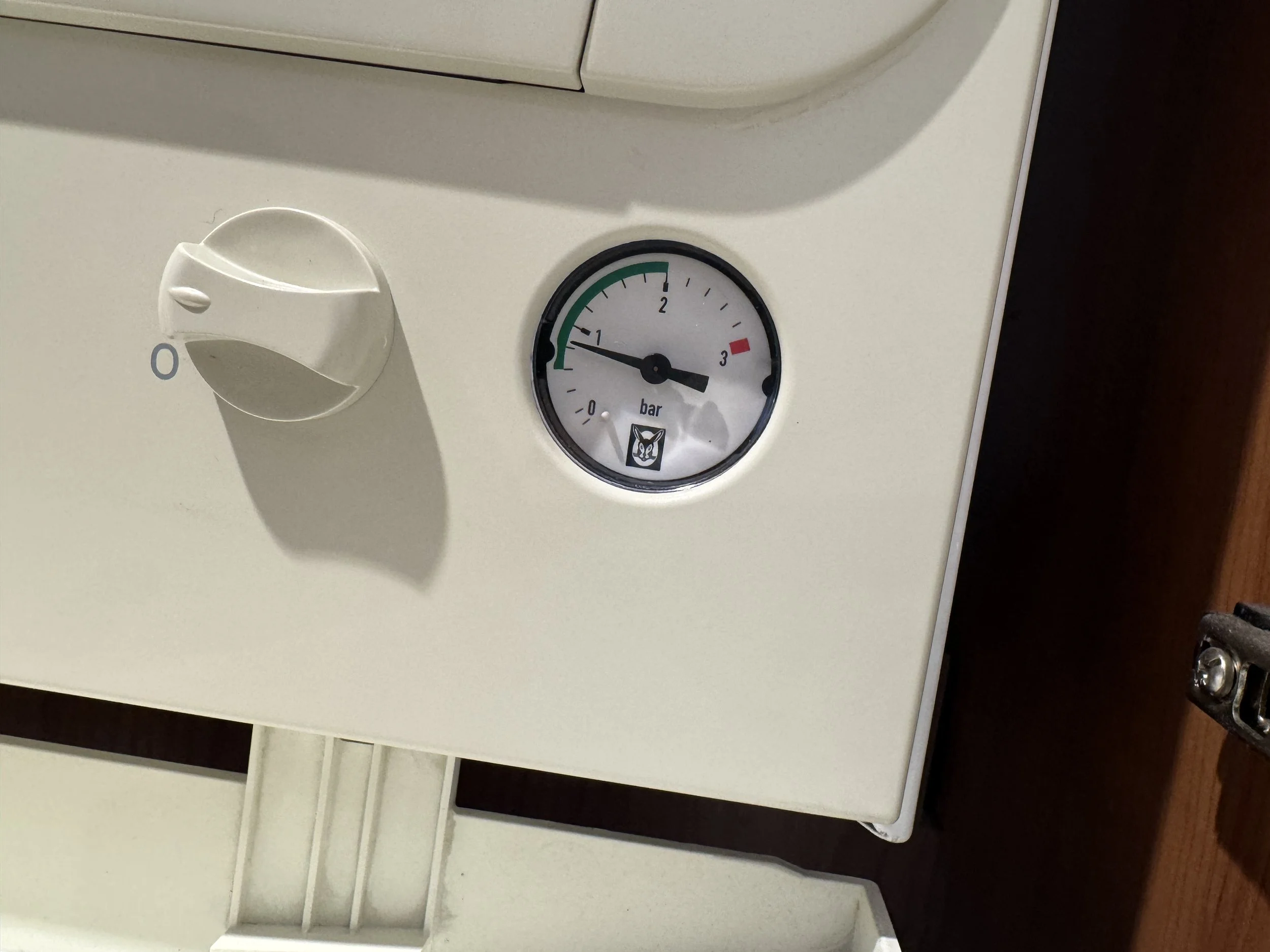 Close-up of a white electronic device with a pressure gauge and a control knob.