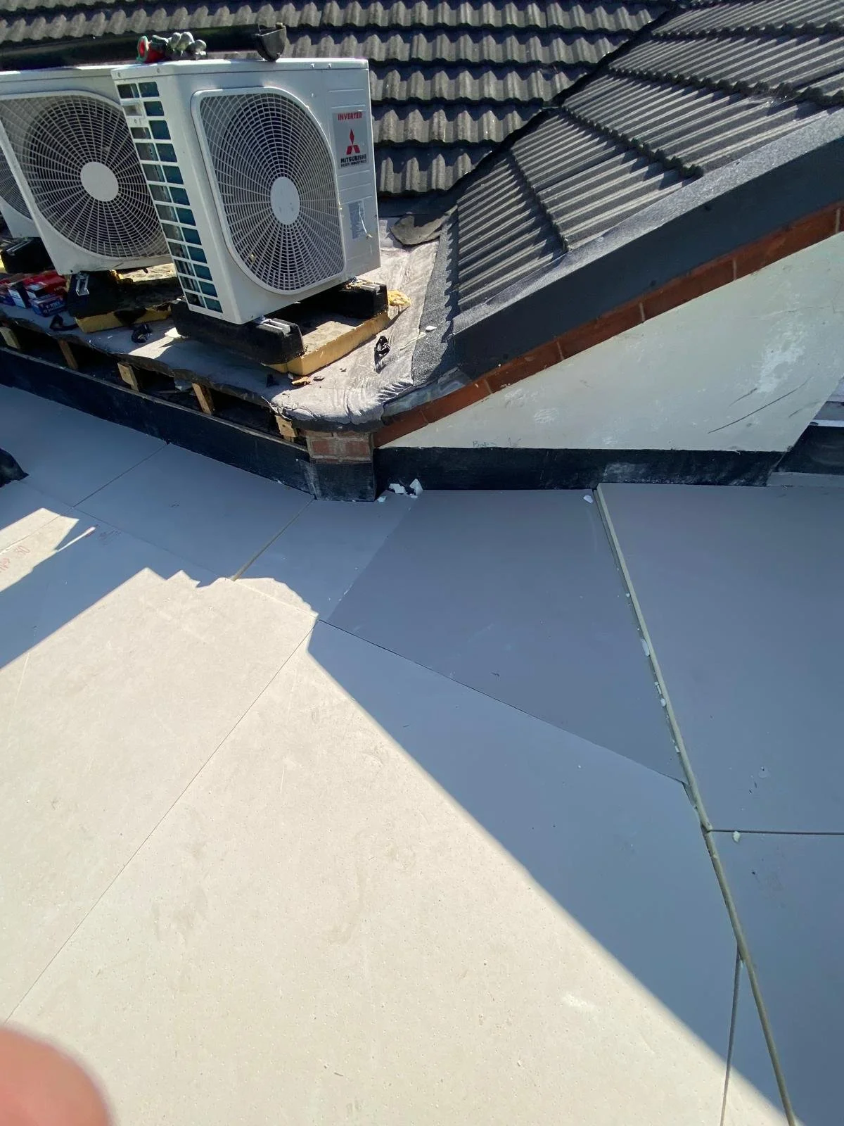 Roof with air conditioning units installed on top and a section of flat roof below.
