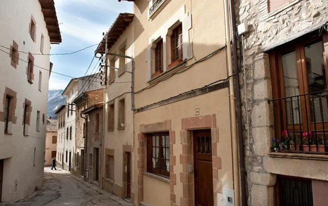 Calle empedrada de Viladrau entre casas con fachadas de piedra, balcones y puertas de madera