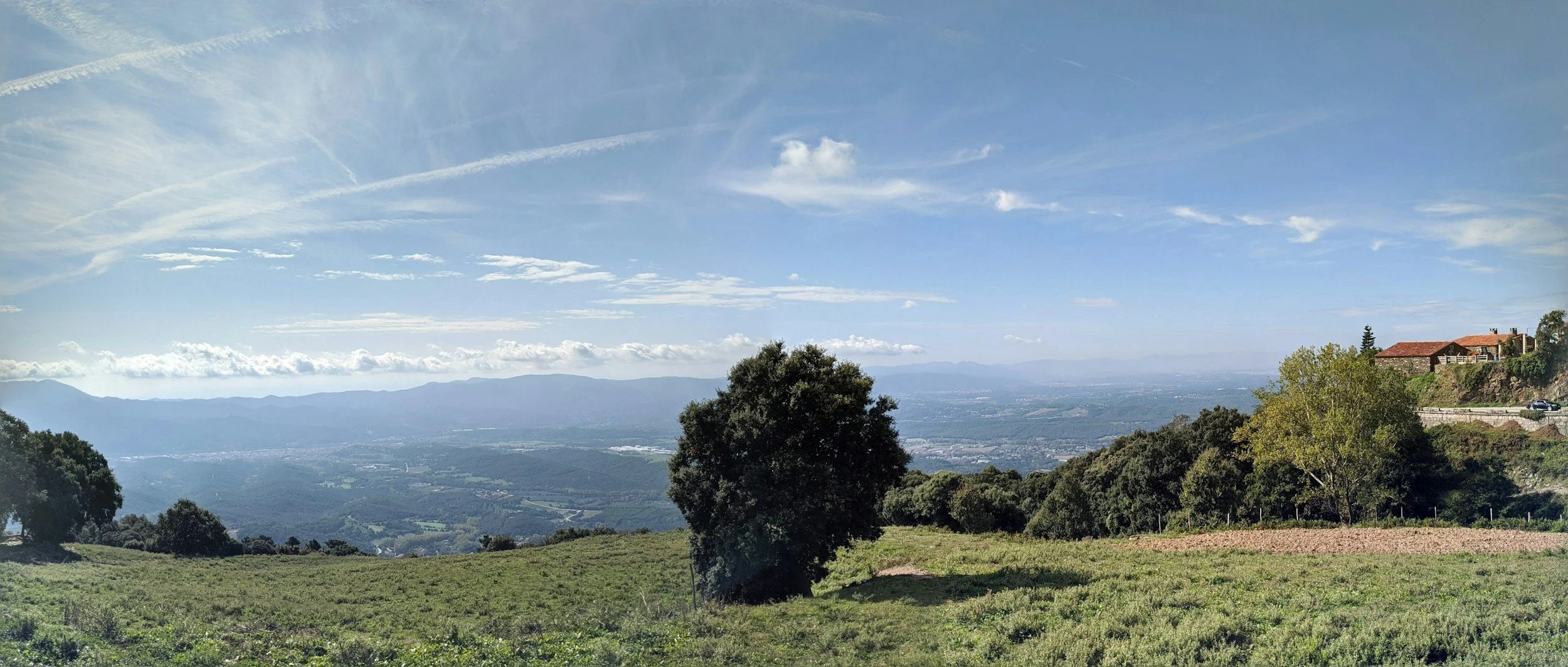 Paisaje abierto con prados, árboles y montañas en el horizonte
