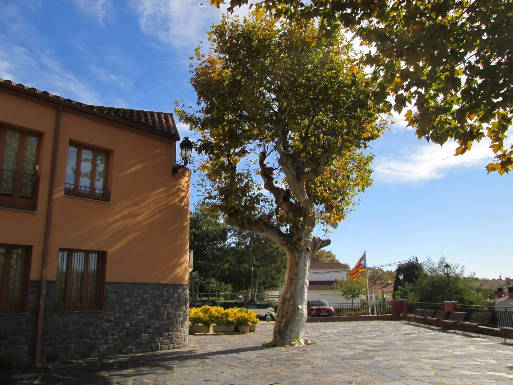 Plaça de la Vila de Campins, con el Ayuntamiento y árboles junto al espacio peatonal