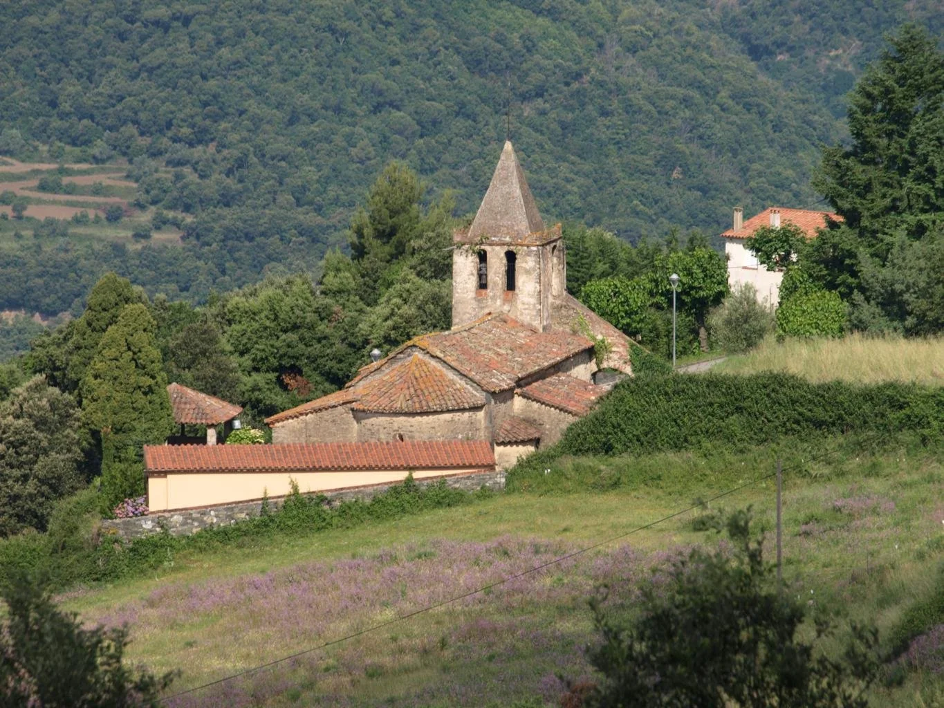 Iglesia de Sant Esteve de La Costa del Montseny entre campos y montañas arboladas