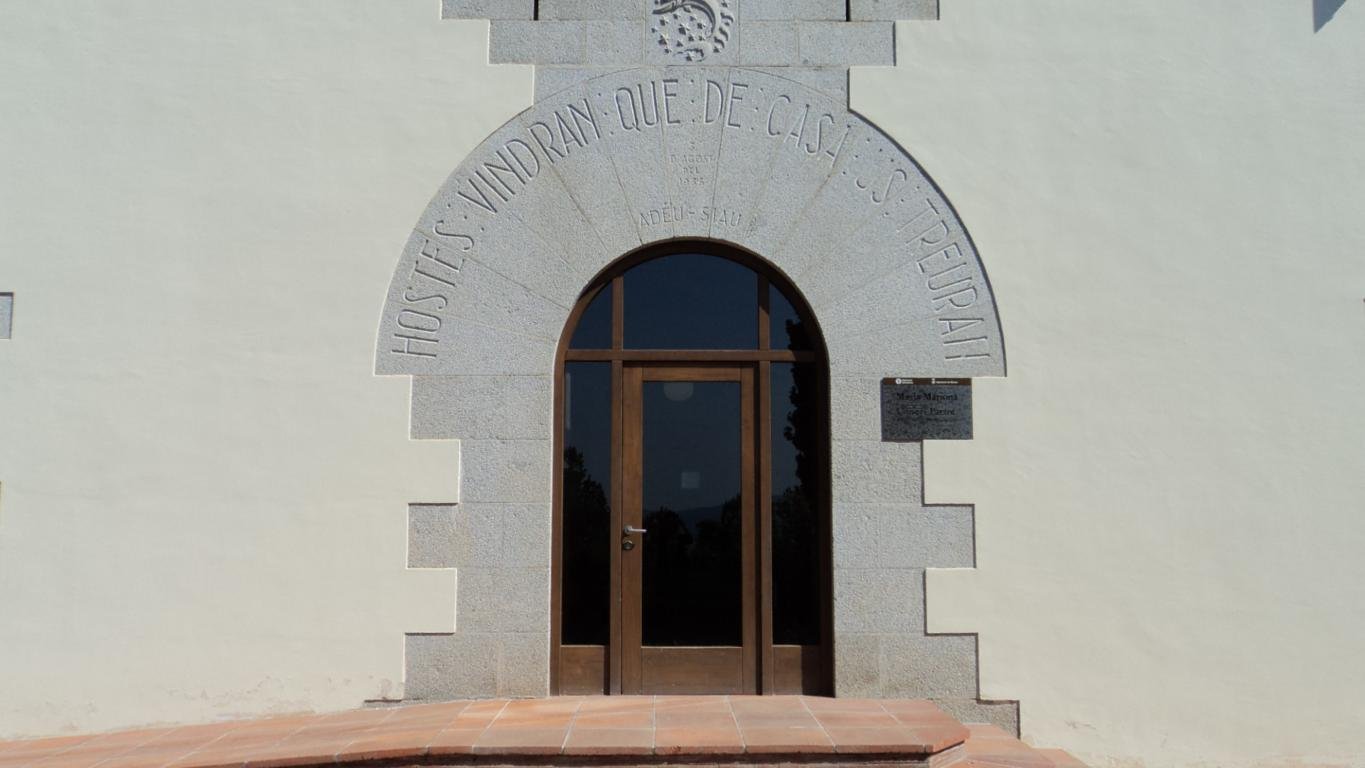 Puerta de entrada de Masia Mariona, con el arco de piedra y la inscripción dedicada a la memoria de la familia Patxot