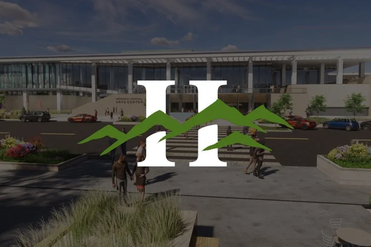 People walking outside a modern arts center with a parking lot and landscaped area in front