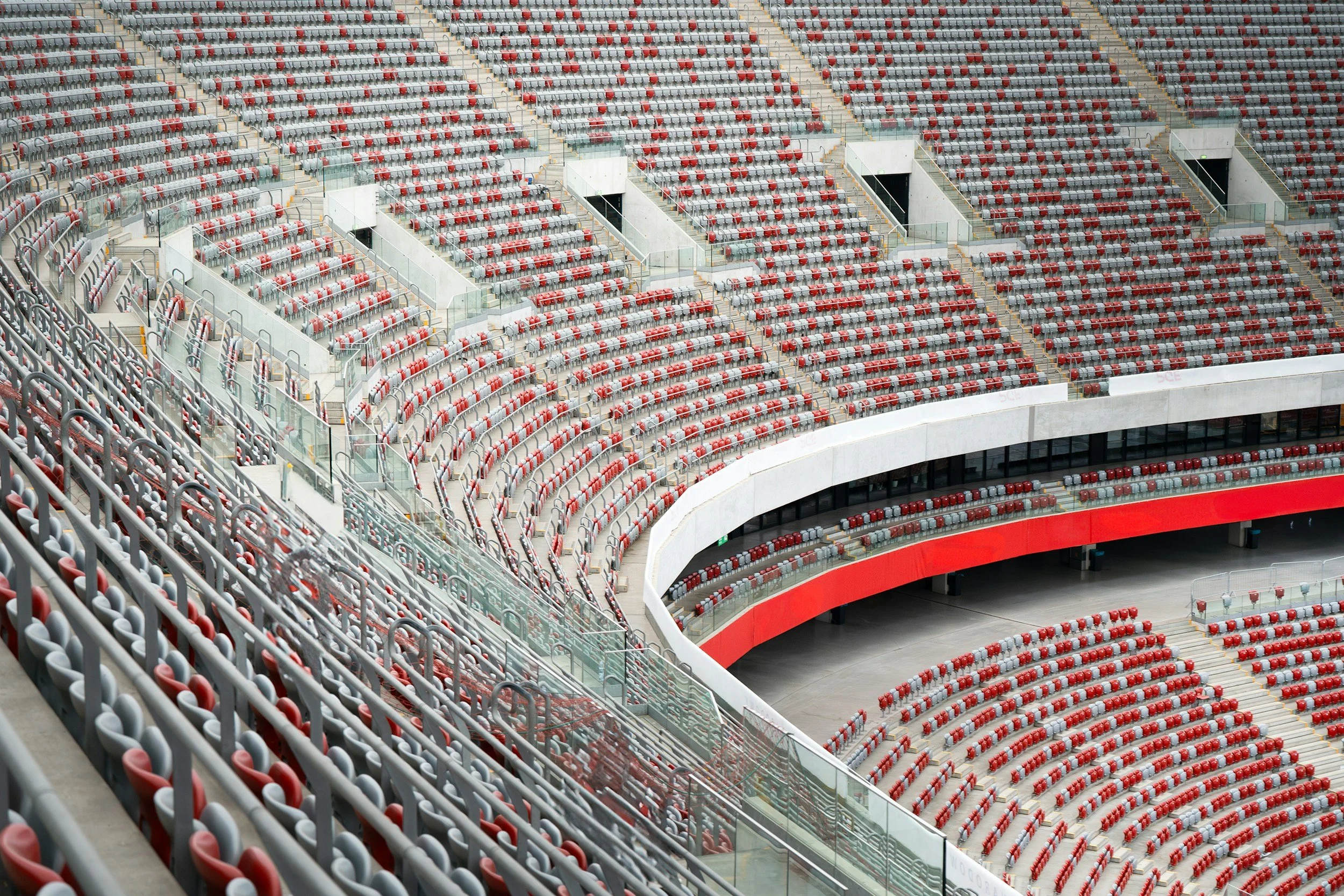 Empty stadium seating with red and gray chairs in a modern sports arena.