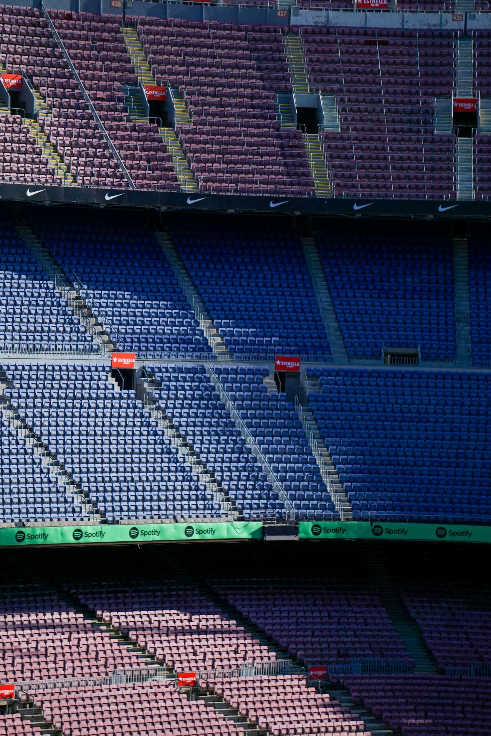 Empty stadium seating with purple, pink, and blue seats, and advertising banners.