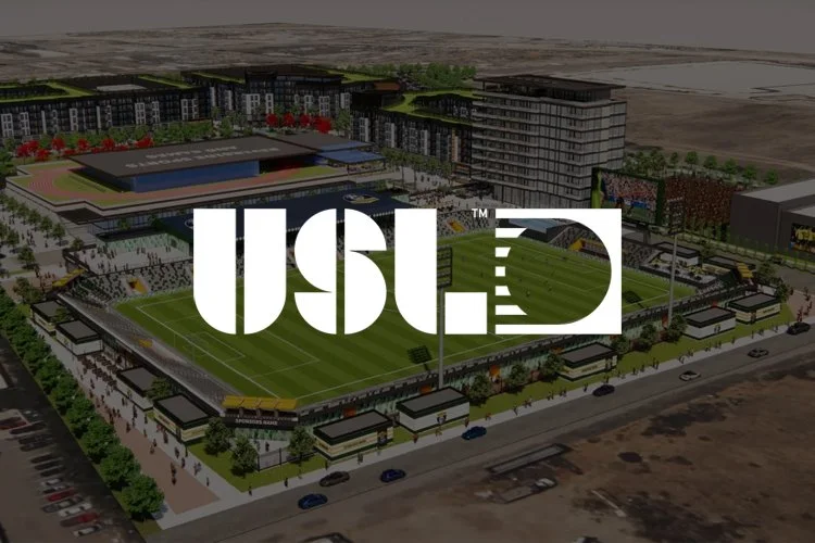 Aerial view of a sports stadium complex with a large logo overlay in the foreground. The stadium features a green playing field, surrounding seating areas, and adjacent buildings, with parking lots and roads nearby.