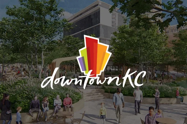 A busy urban park in downtown Kansas City with people sitting, walking, and socializing, featuring modern buildings and lush greenery, overlaid with the Downtown KC logo.