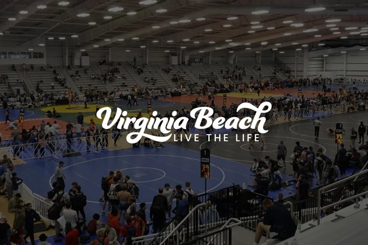 Indoor sports arena with people walking and sitting, multiple basketball courts, Virginia Beach branding overlay, and