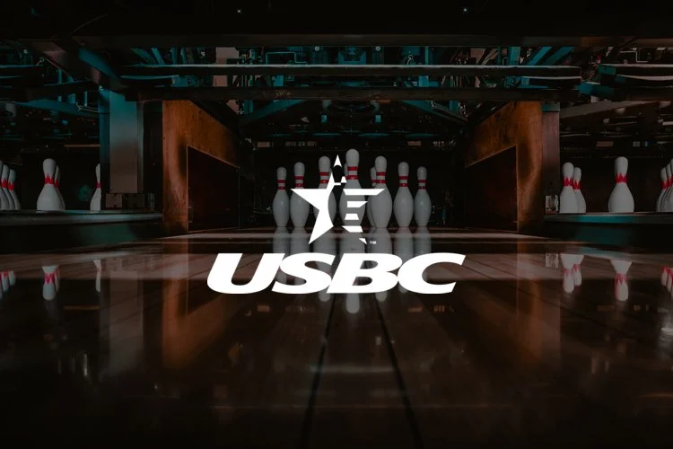 Bowling alley with pins set up at the end lane and the USBC logo overlayed in the center.