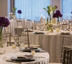 Elegant banquet table with floral centerpieces, dinnerware, and glassware set for a formal event.