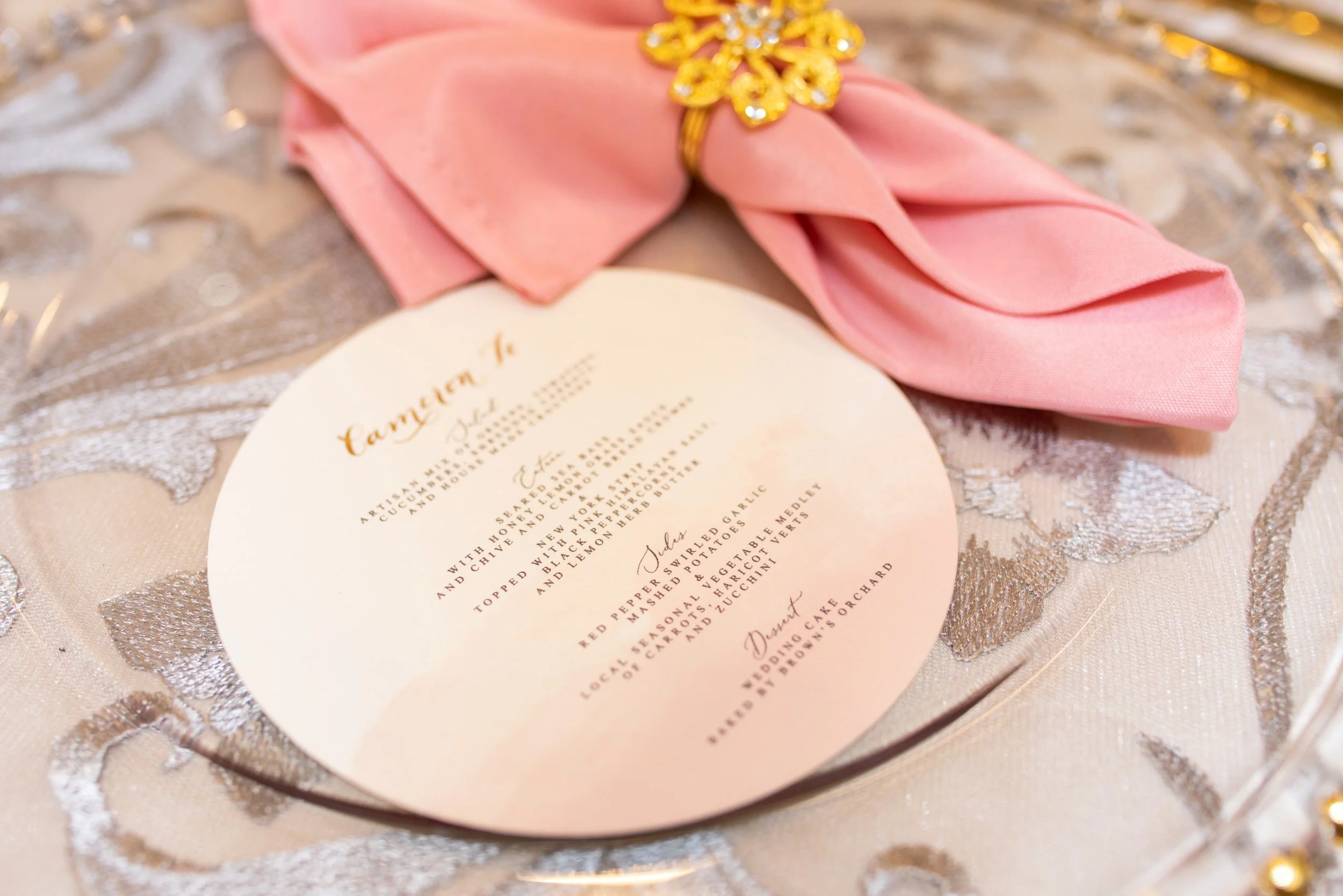 Elegant wedding menu card on lace tablecloth with pink silk napkin and gold jewelry