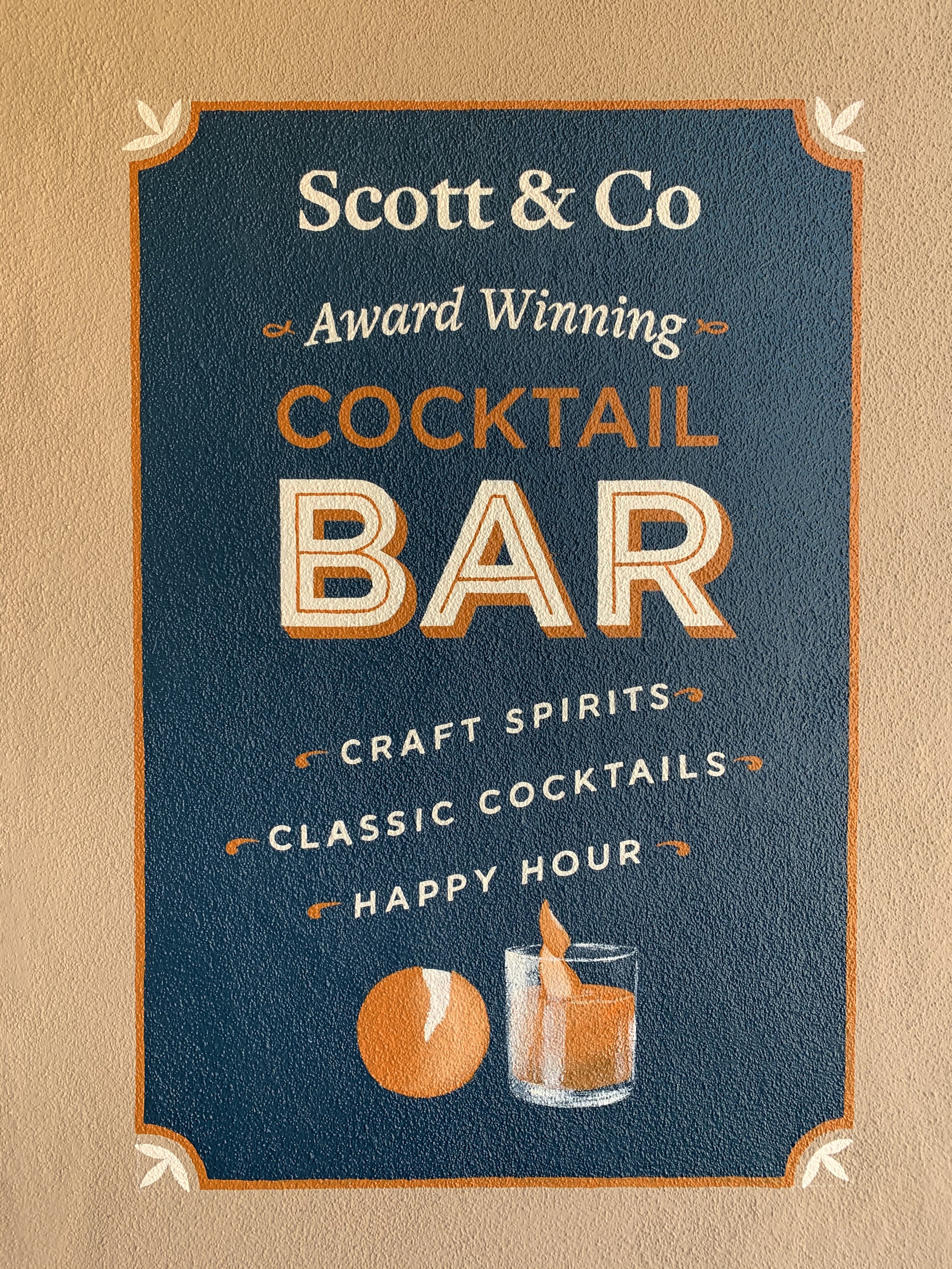Sign for Scott & Co Cocktail Bar featuring craft spirits, classic cocktails, and happy hour, with illustrations of an orange and a cocktail glass.