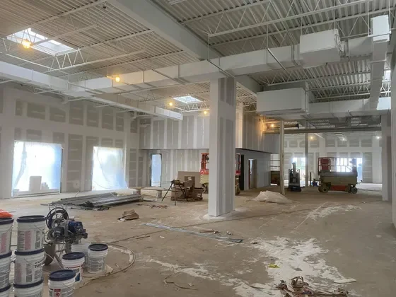 Interior of a building under construction with unfinished walls, construction materials, and equipment scattered around.