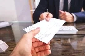 Person handing a receipt to another person at a table.