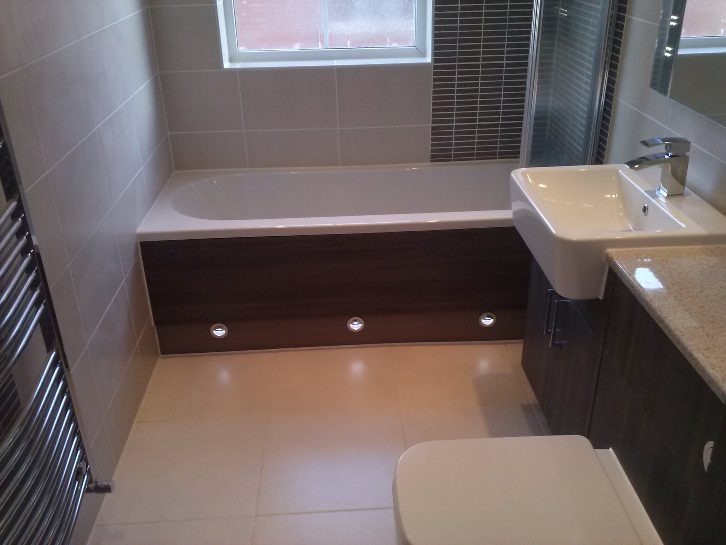Modern bathroom with bathtub, sink, and beige tiled walls