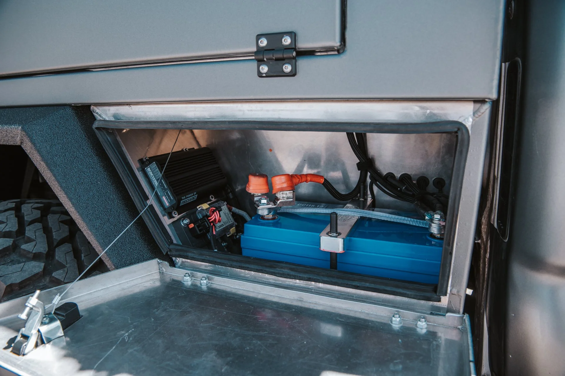 Close-up of an electric vehicle battery system installed inside a metallic compartment, showing wires and components.