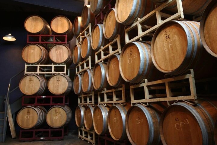 Wooden barrels stored on racks in a wine cellar or brewery.
