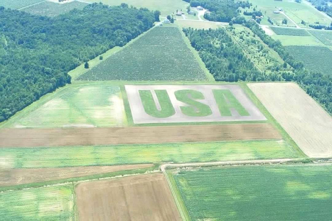 Aerial view of farmland with large planting of the USH logo in the center