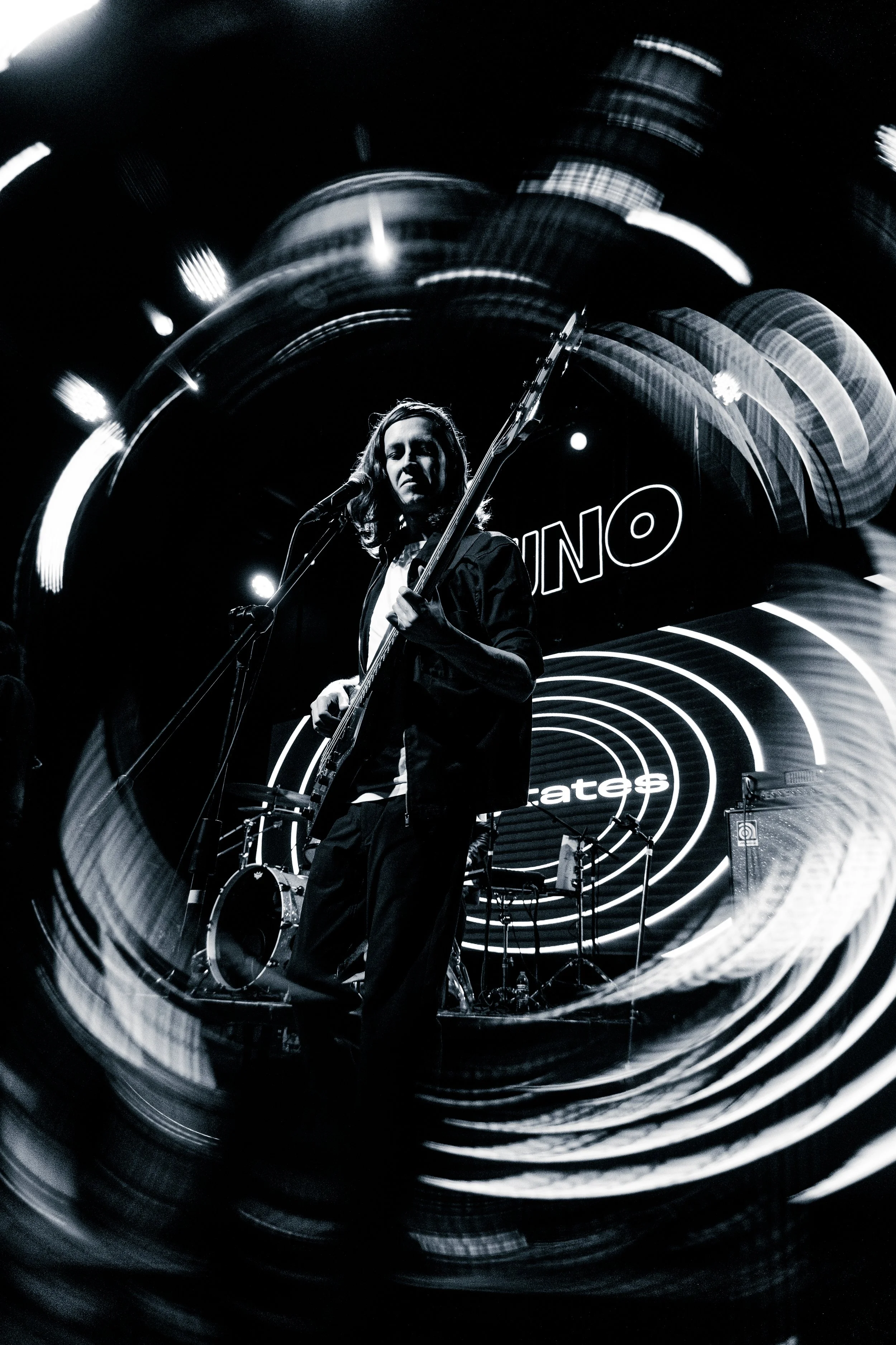 Músico tocando la guitarra en un escenario con luces y fondo digital que dice 'UNO' en letras grandes.