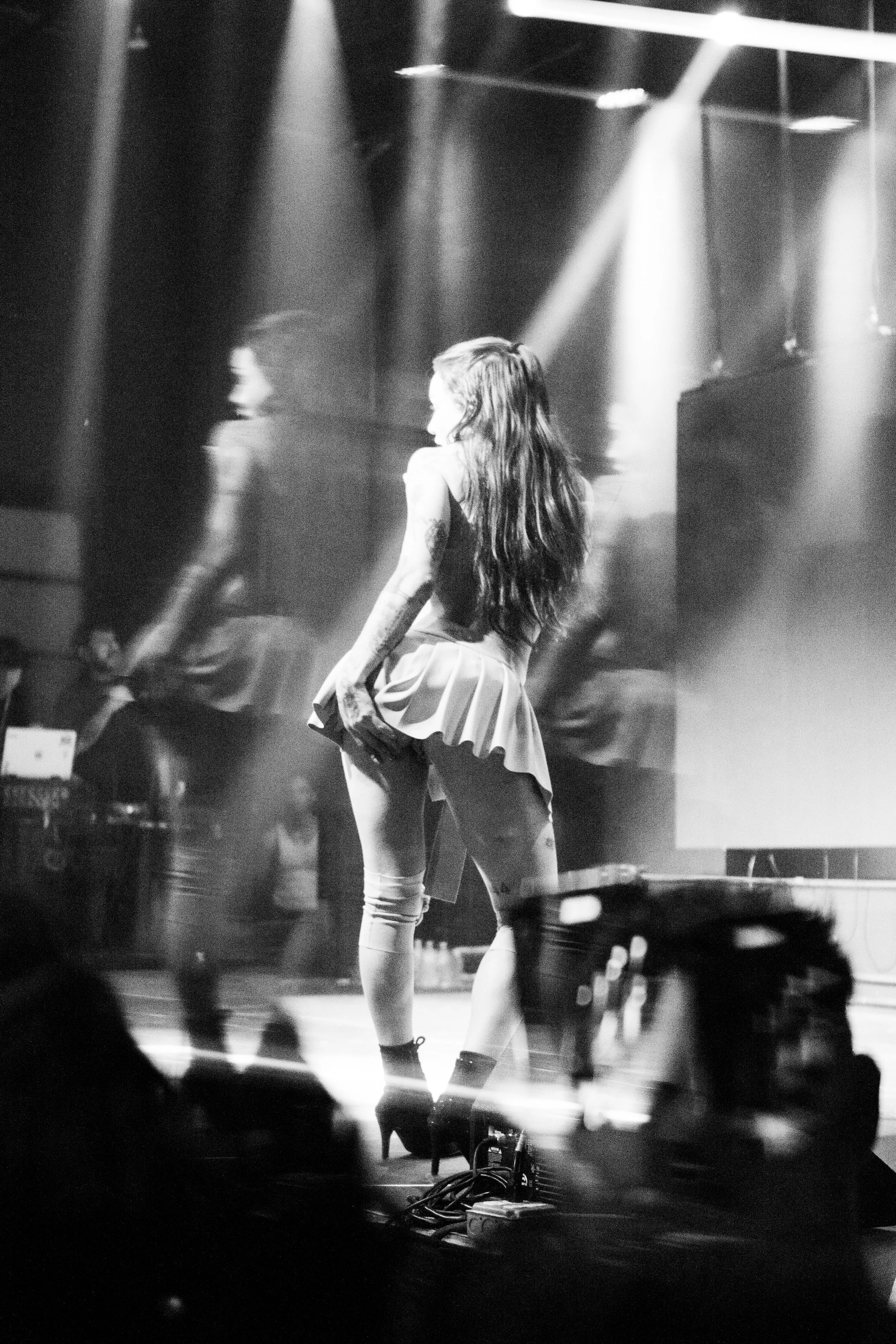 Mujer bailando en un escenario con iluminación de escenario, vista en blanco y negro.