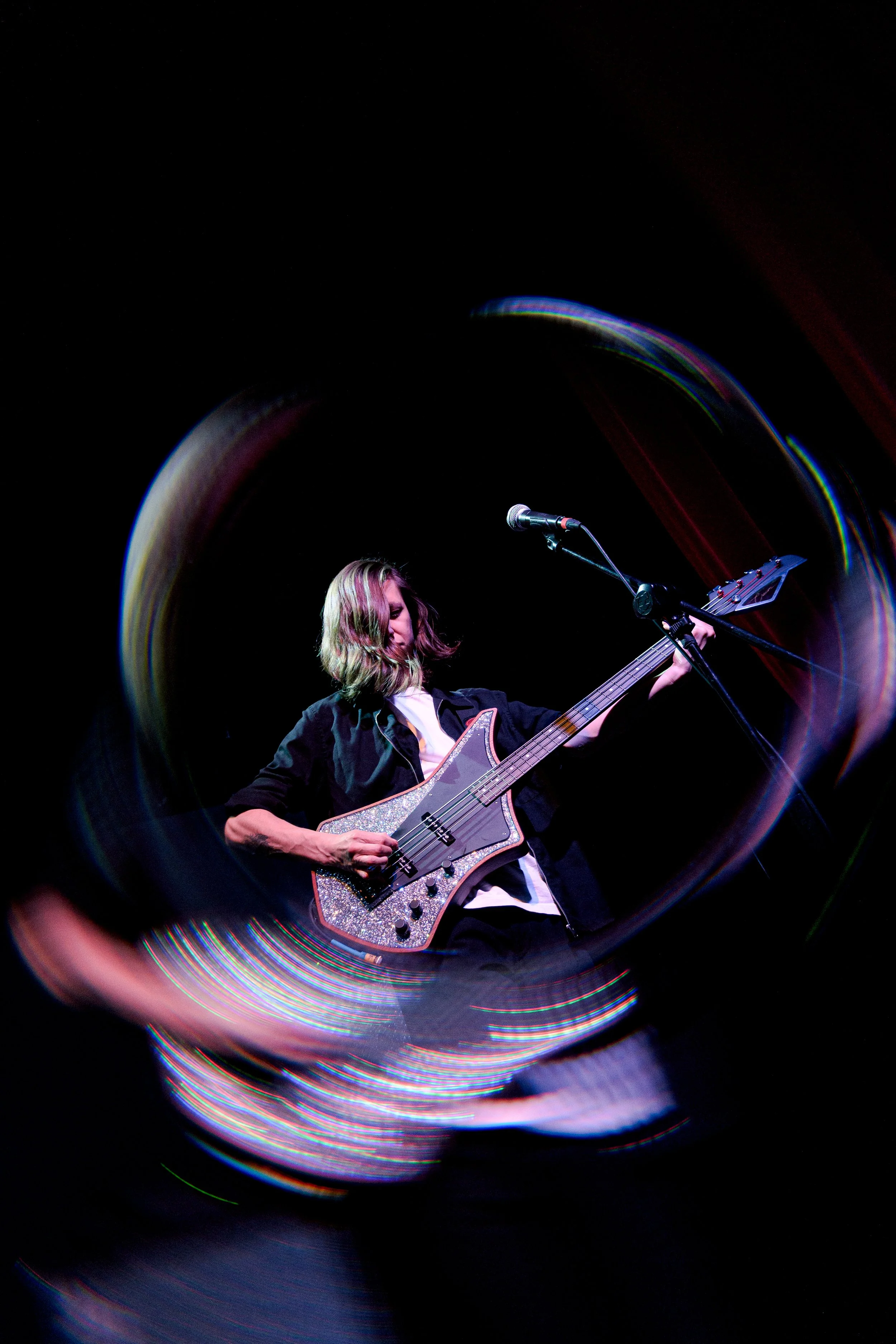Joven tocando la guitarra en un escenario con efectos de luz y movimiento