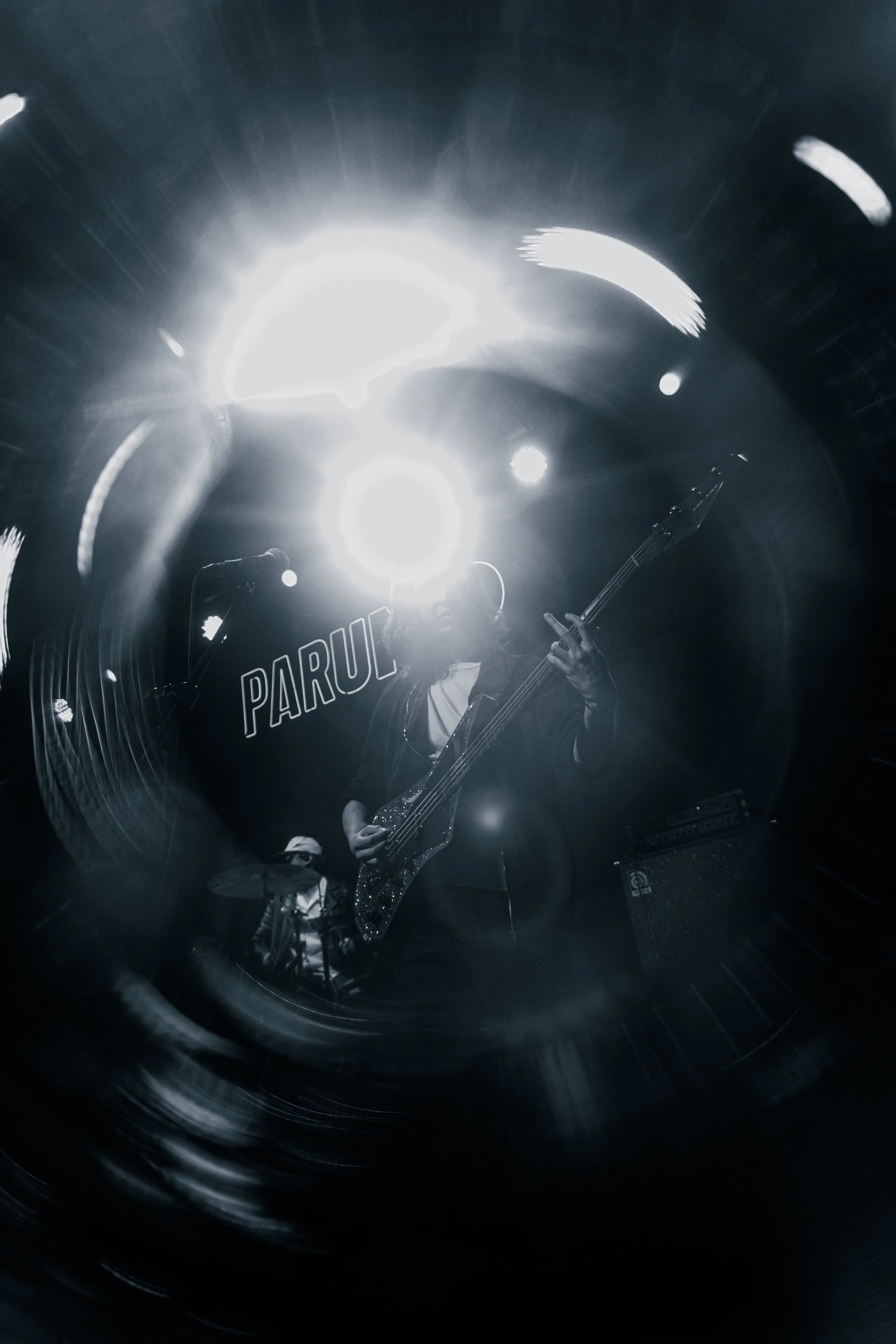 Un músico tocando la guitarra en un escenario con luces brillantes y efectos de luz en modo negro y blanco.