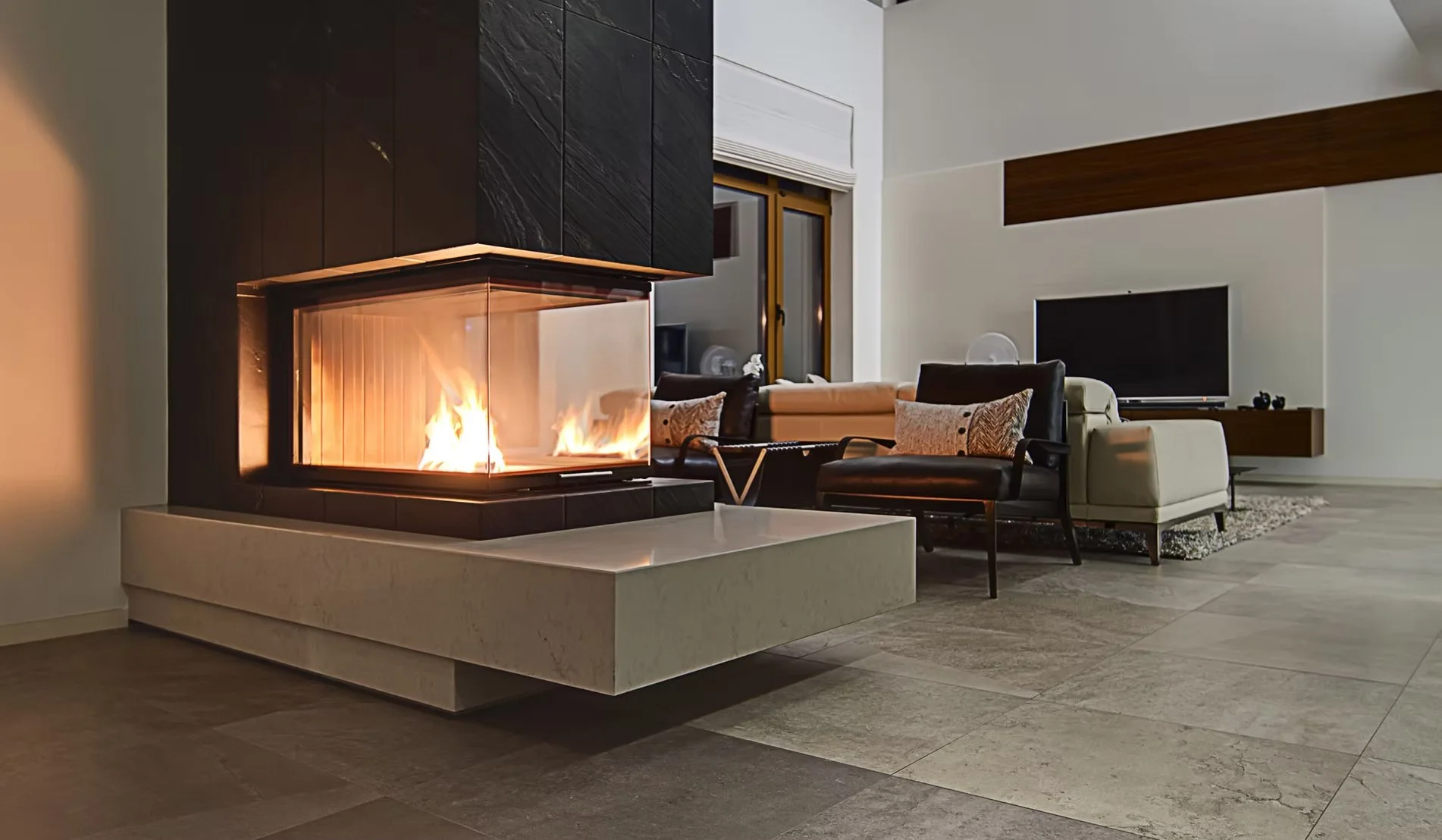 Sala moderna con chimenea encendida, sillones y televisor en la pared