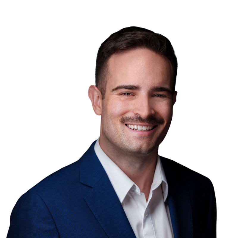 Headshot of a smiling man in a blue suit and white shirt against a white background.
