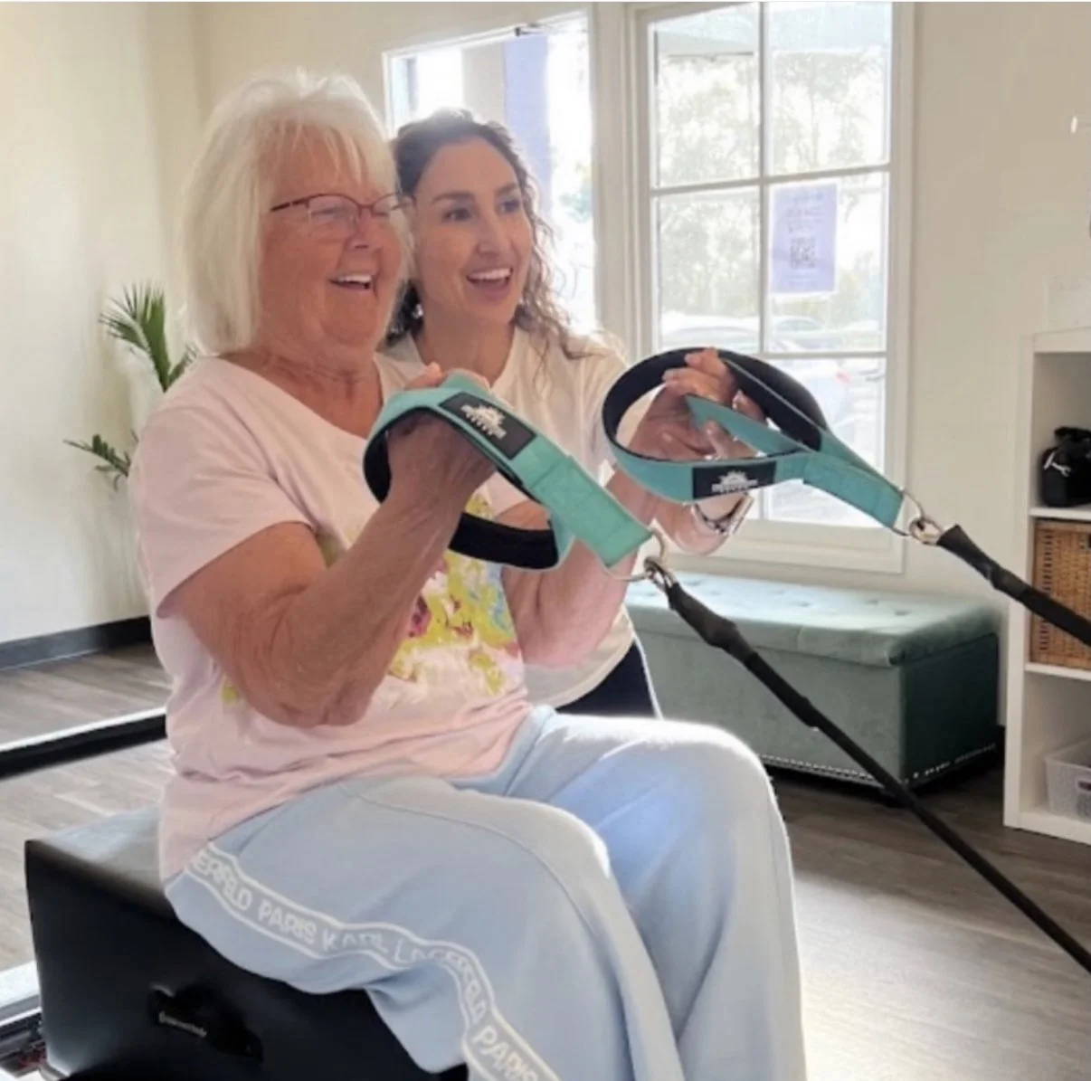 Women's health specialist guiding a smiling client through a reformer Pilates intro session at Revive PT & Pilates in Encinitas, CA