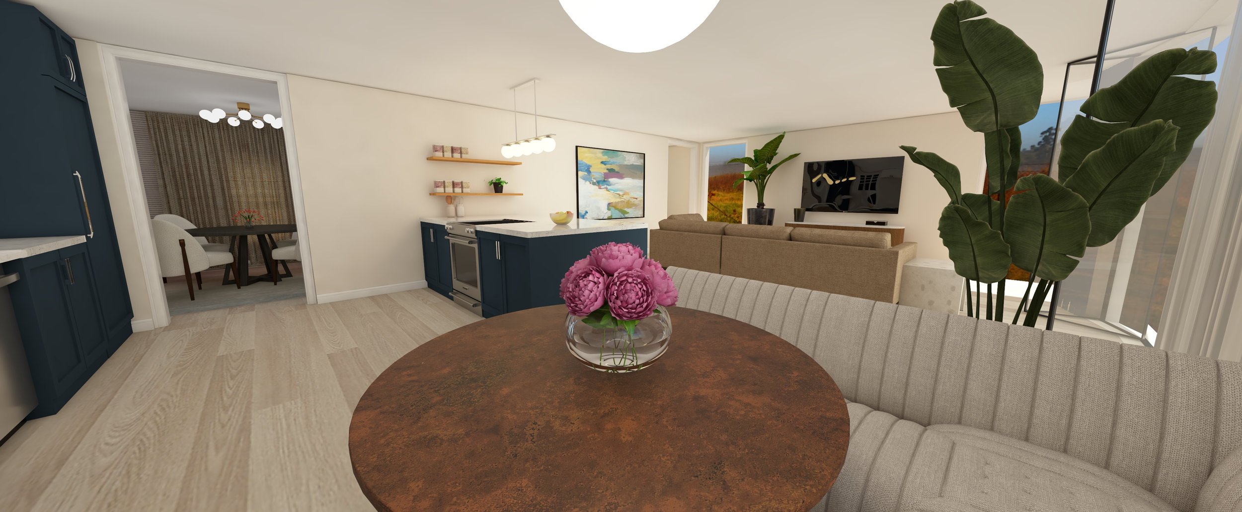 Interior of a modern living room with a beige sofa, a large TV, and green houseplants. A round dining table with pink flowers is in the foreground. Open kitchen with navy blue cabinets and a kitchen island is visible, with a small dining area with wh