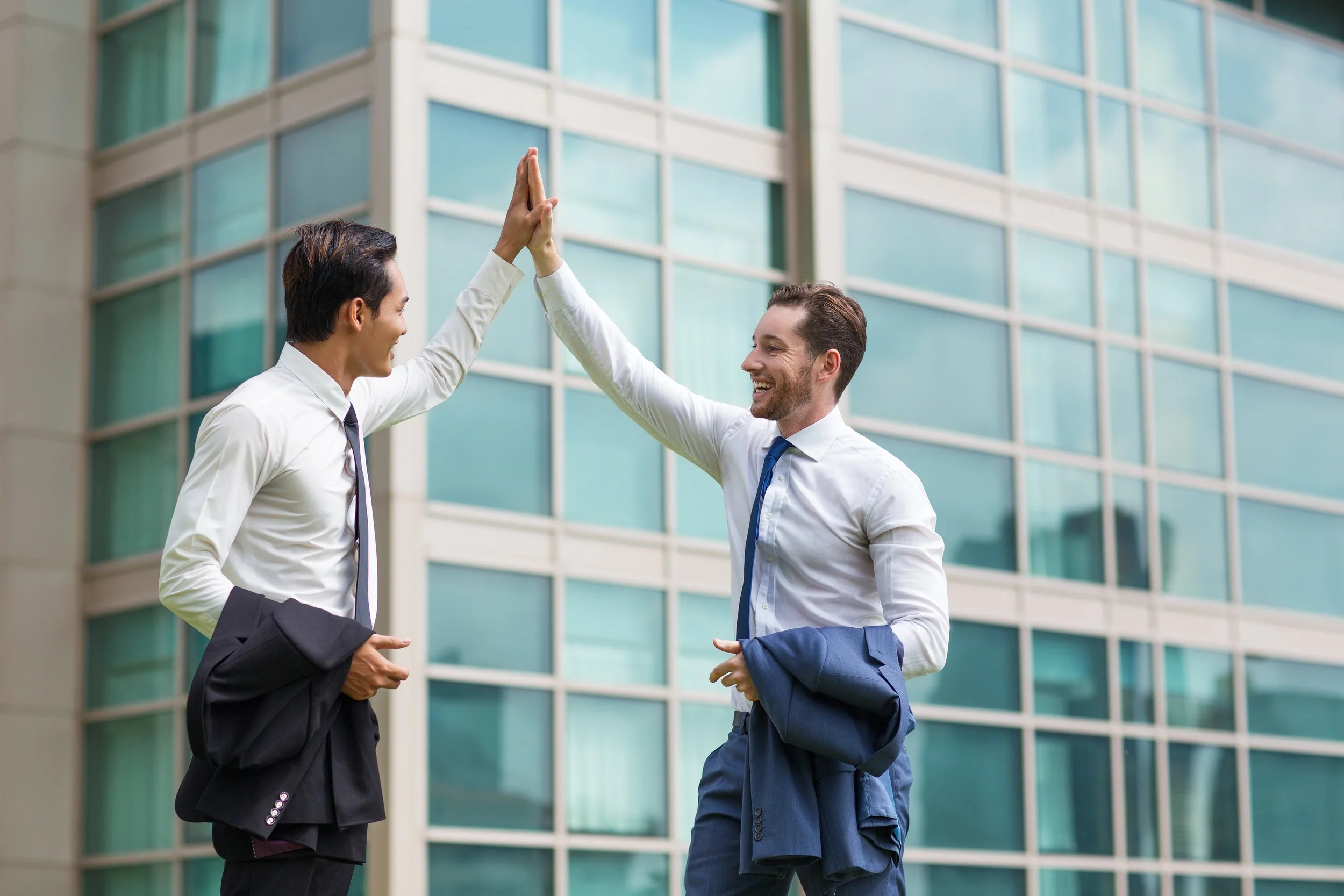 Businessmen in white shirts sharing a joyful high-five for career success - Calm Harbor Counseling