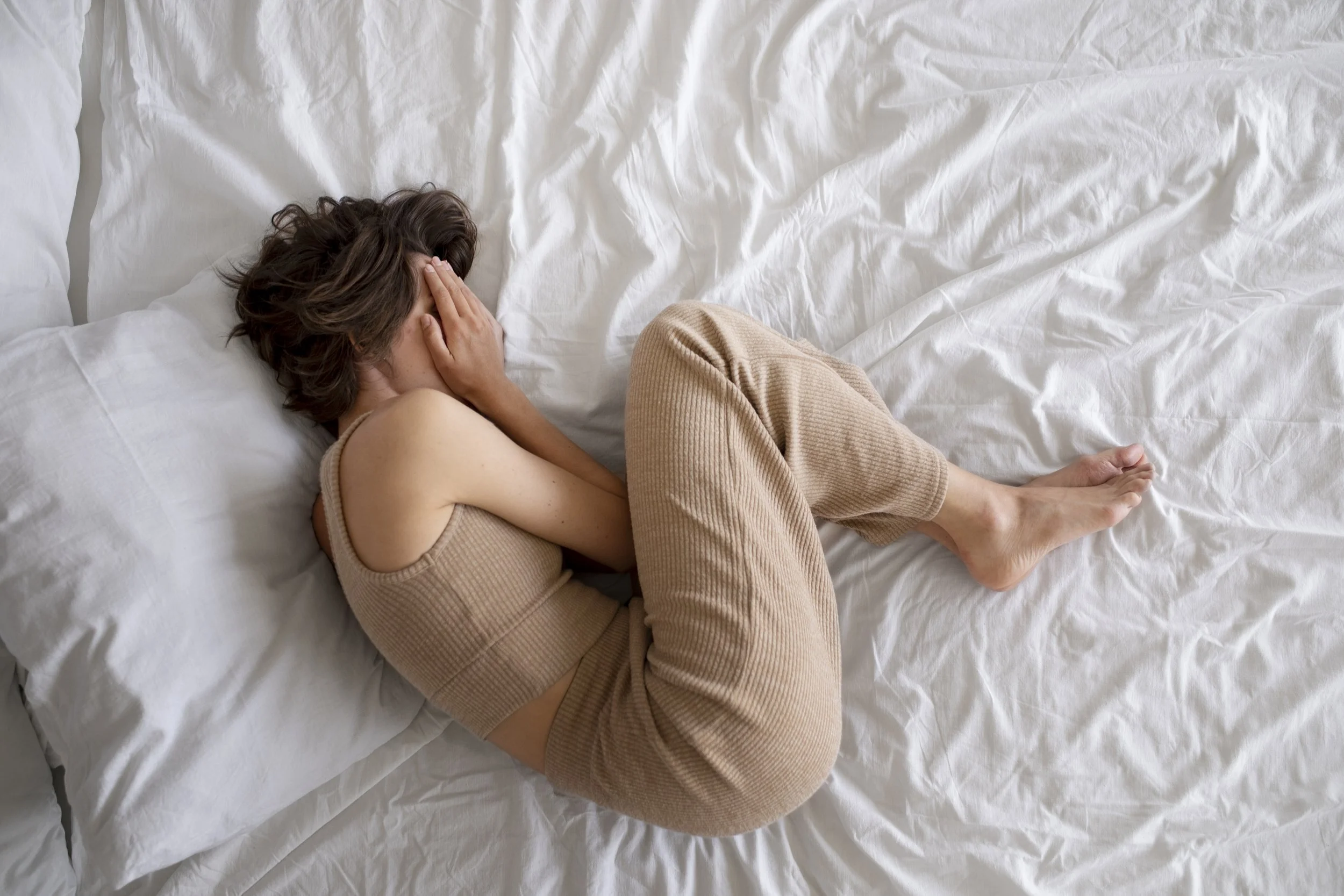 A woman experiencing severe anxiety while lying down in bed - Calm Harbor Counseling