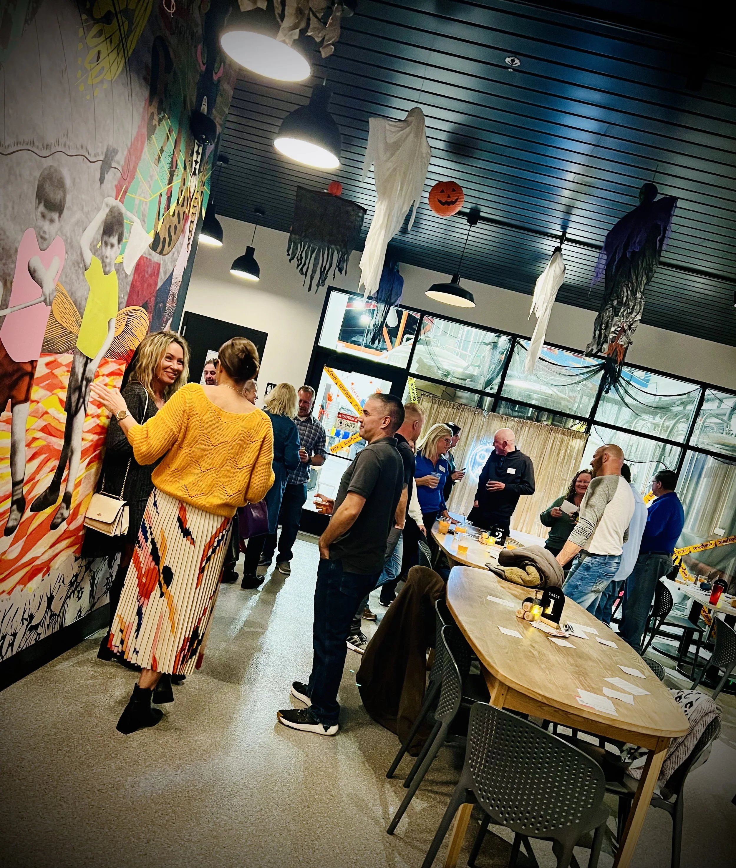 Singles standing and chatting together at a lively in-person dating event in a modern venue. Cocoon Brewing Company in De Pere, Wisconsin