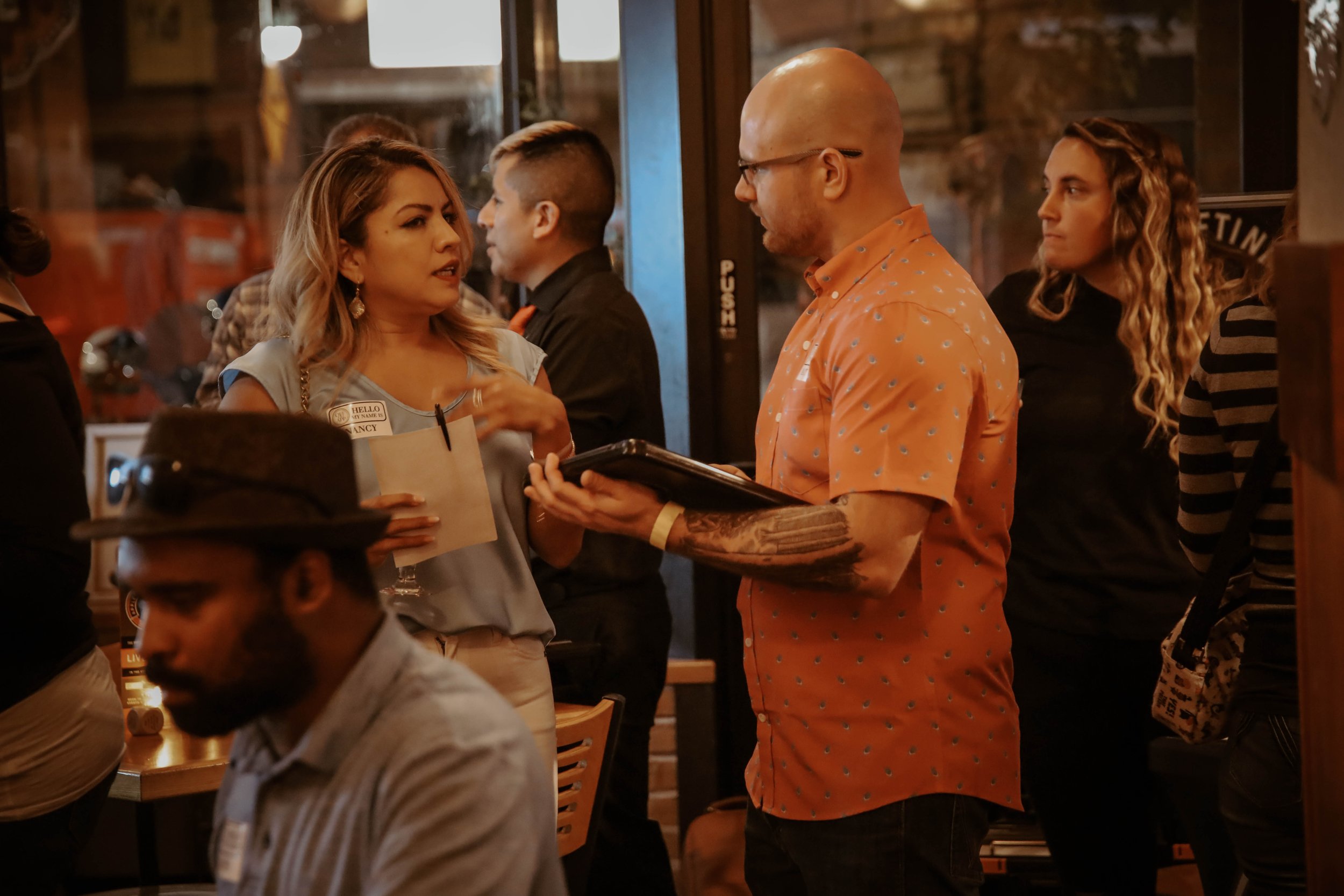 “Group of singles mingling and talking at a welcoming in-person off the app dating event.”