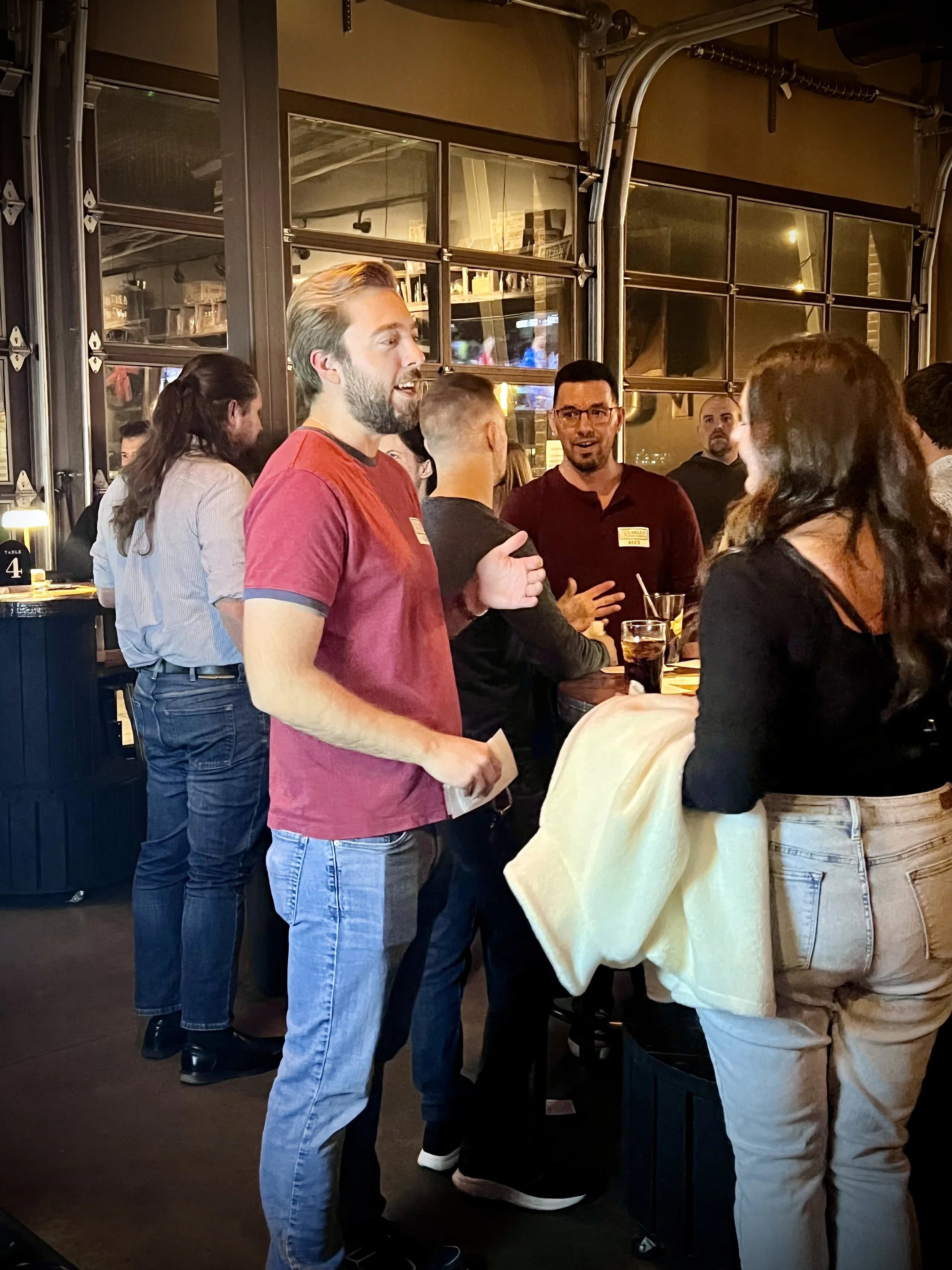 Singles standing and talking together at a casual in-person dating event inside a bar
