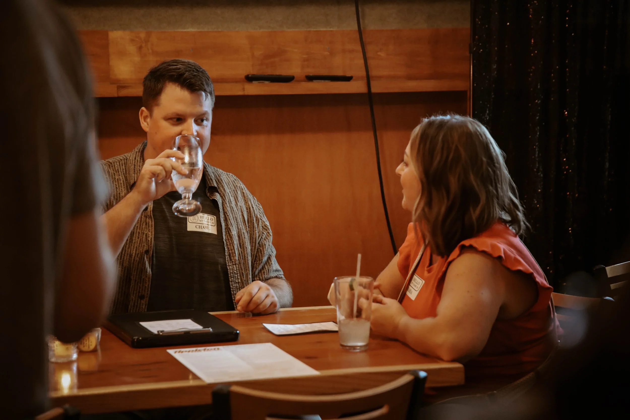 “Two people seated across from each other having a relaxed conversation at an in-person dating event.”