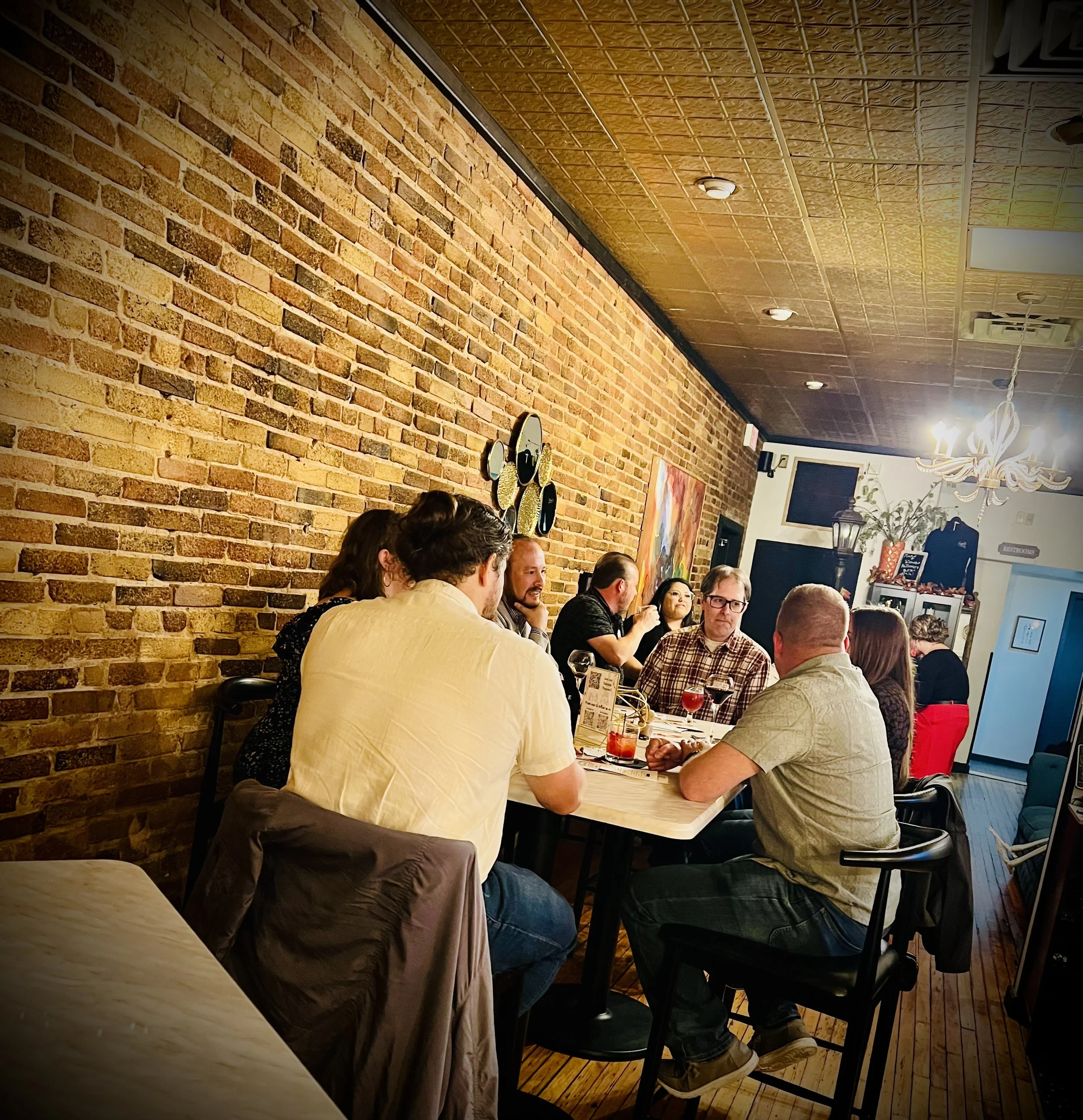 Group of singles seated at tables talking and sharing drinks during an in-person dating event. hosted at Flights Wine and Cocktail Club in Oshkosh, Wisconsin
