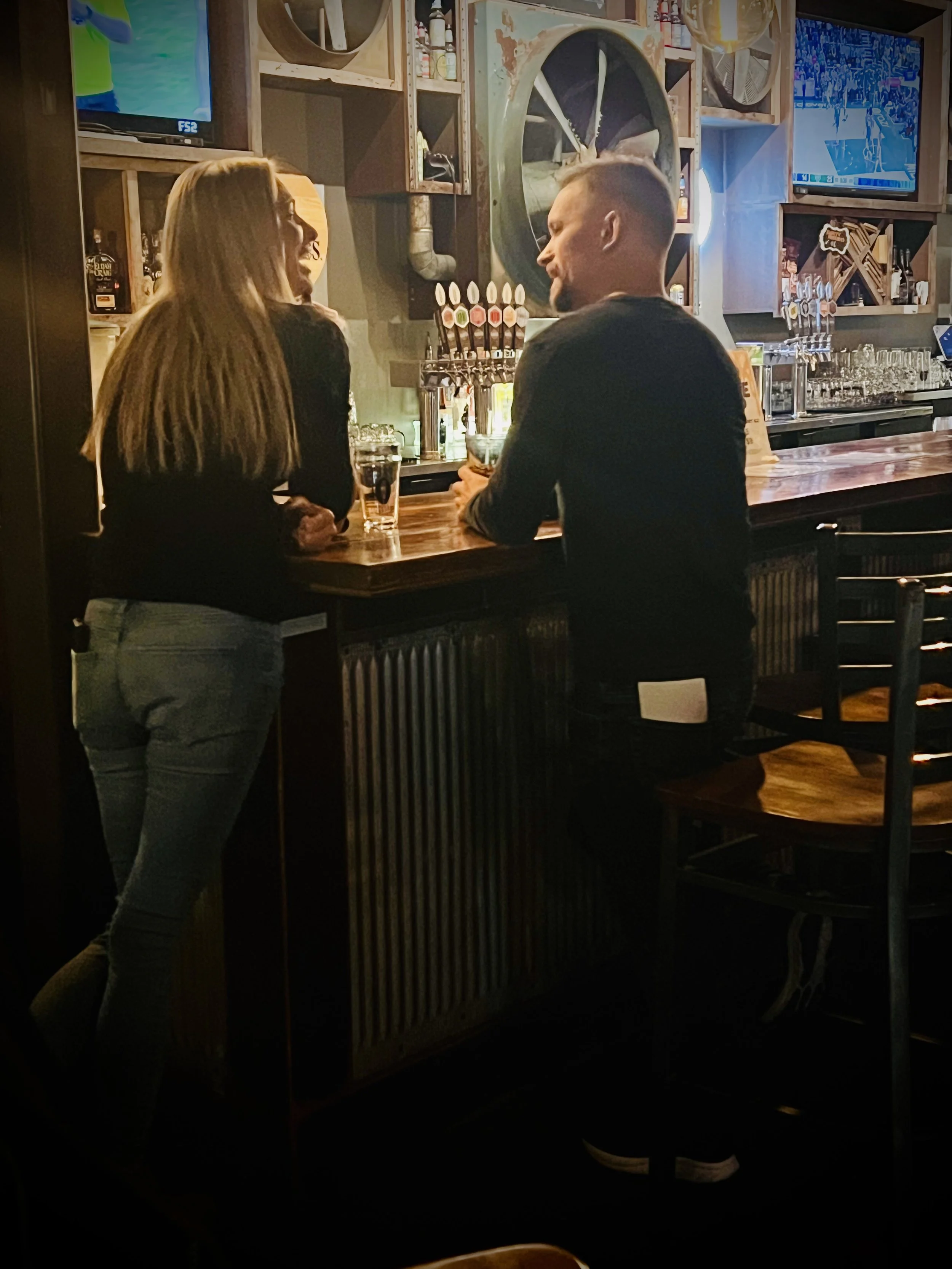 Man and woman seated at a bar talking together during a casual in-person dating event