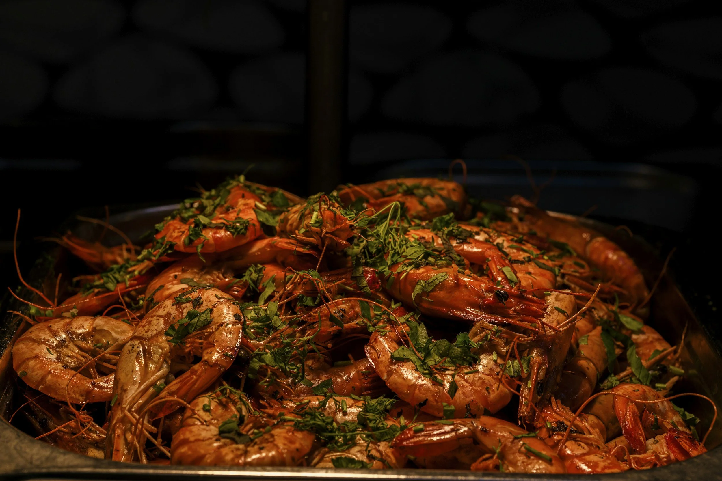 Cooked shrimp garnished with chopped herbs in a serving dish