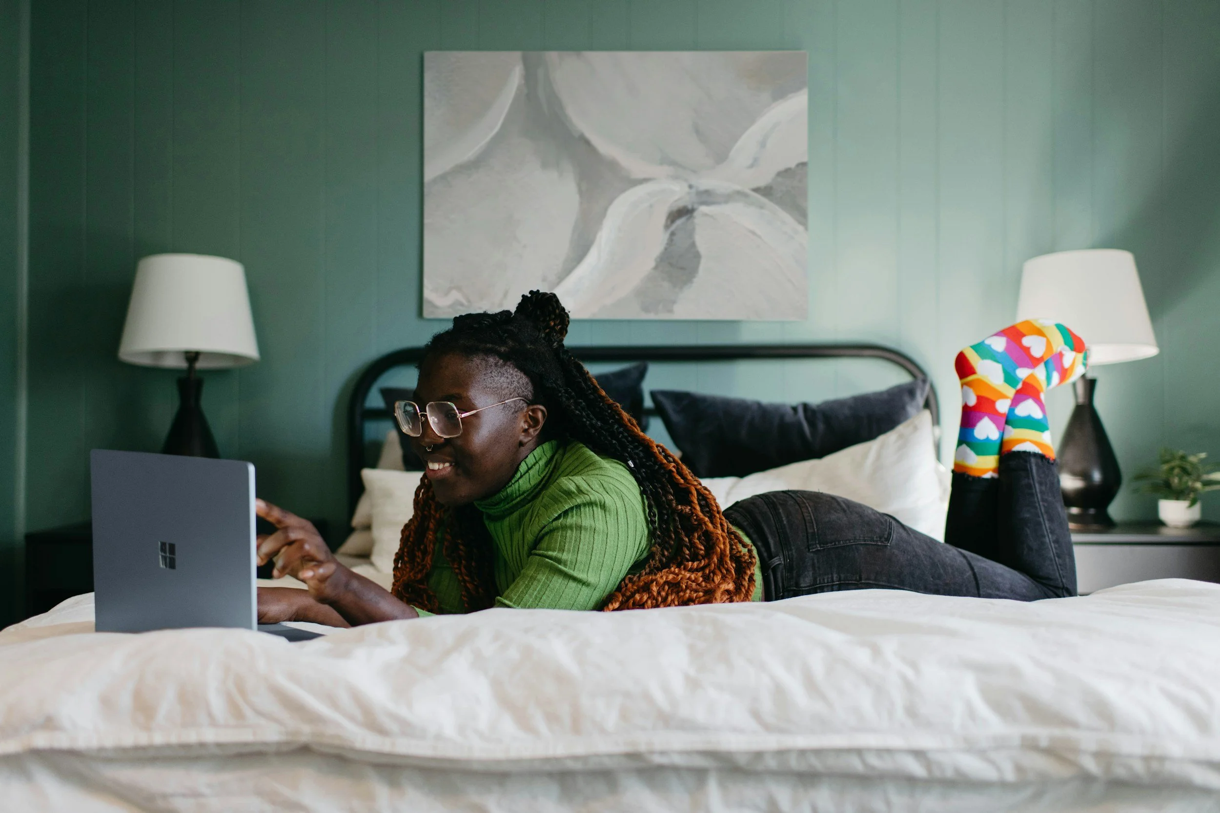 Woman laying on her bed engaged in a virtual telehealth therapy session to help her improve her symptoms of ADHD.