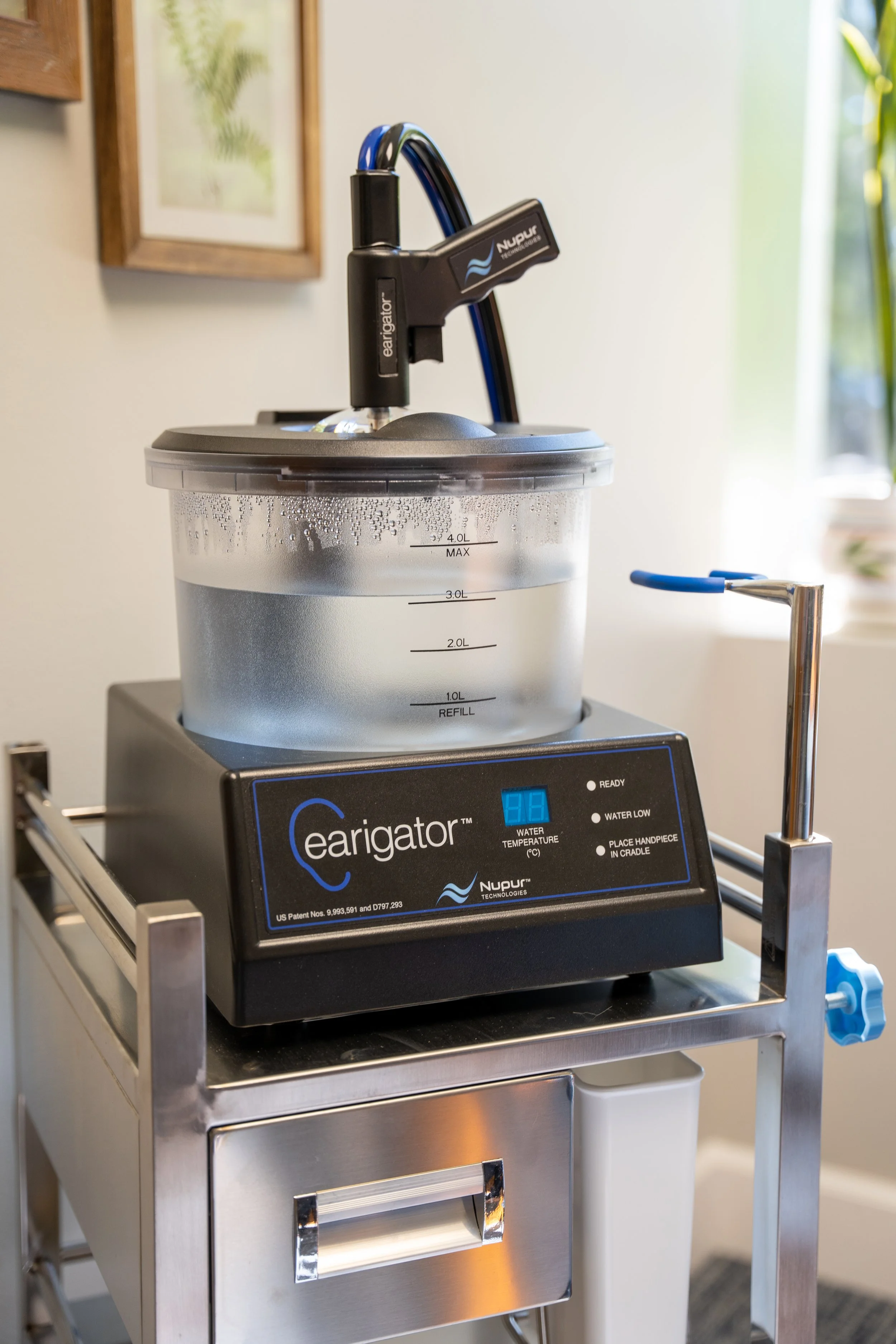 A countertop machine labeled 'earigator' and 'Nupur Technologies' with a digital display, placed on a stainless steel cart in a well-lit room.