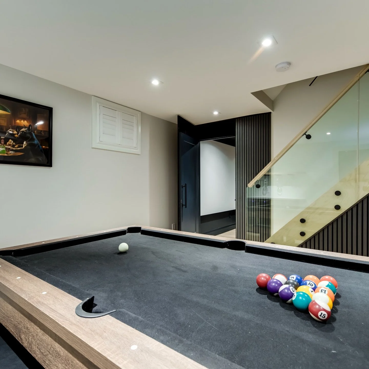 A basement done right 👌
This custom space features a modern games area with a sleek pool table, custom slat accent wall, glass railing staircase, and a built-in bar with wine storage 🍷🎱

And this is just one room.
Behind the hidden door beside the