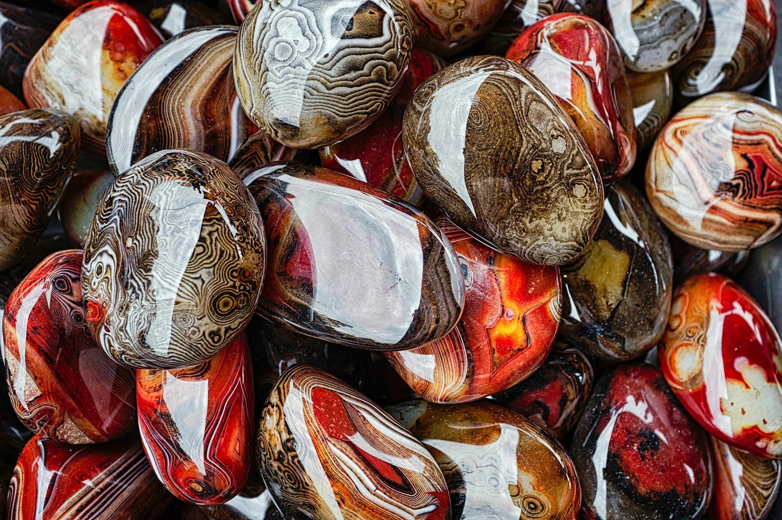 Un groupe de pierres colorées avec des motifs variés en rouge, blanc, beige, et noir.