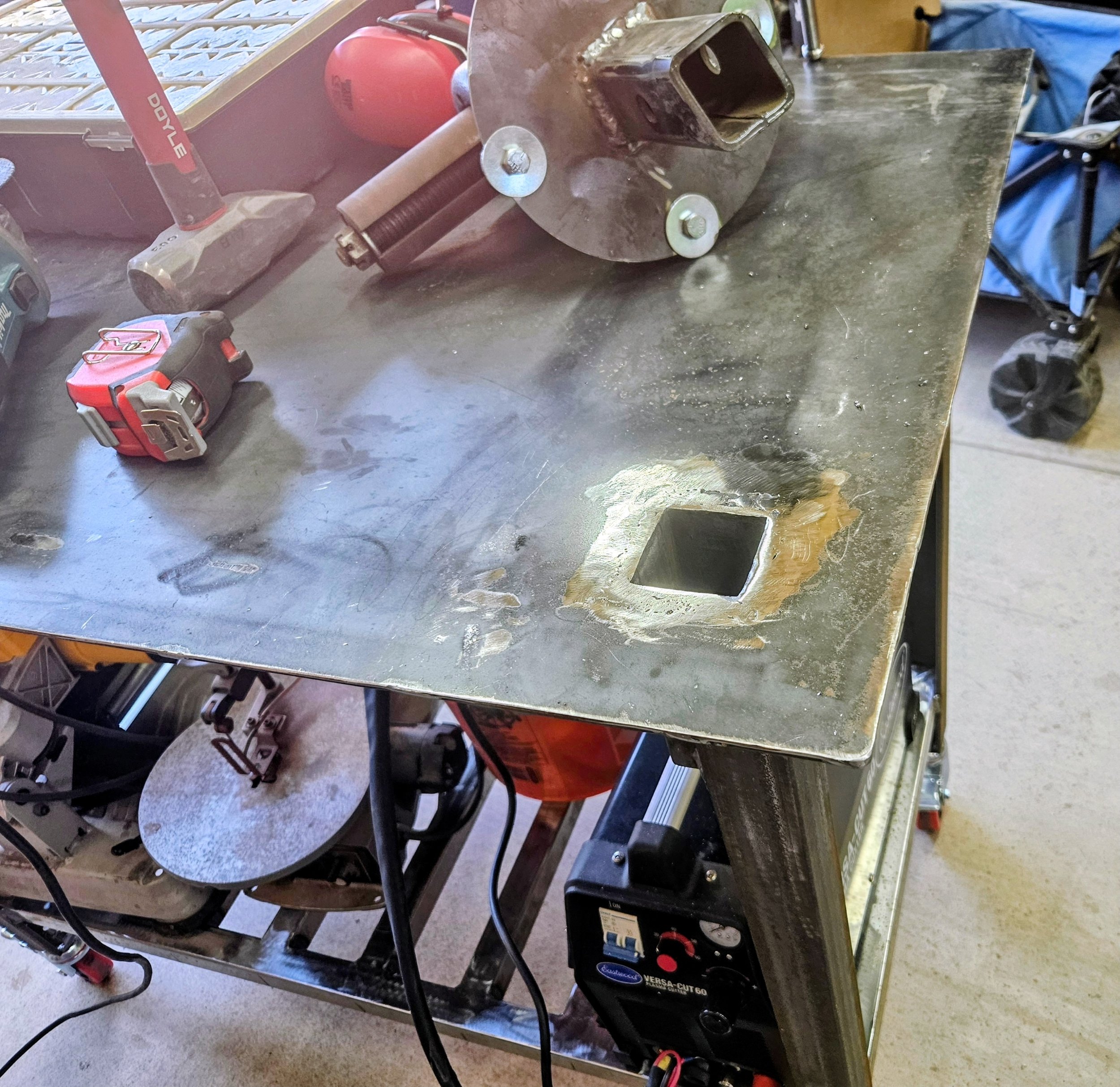 Cut out a 2" square in the corner of the table and welded a receiver hitch coupler flush to the top of the table for changing tools easily.