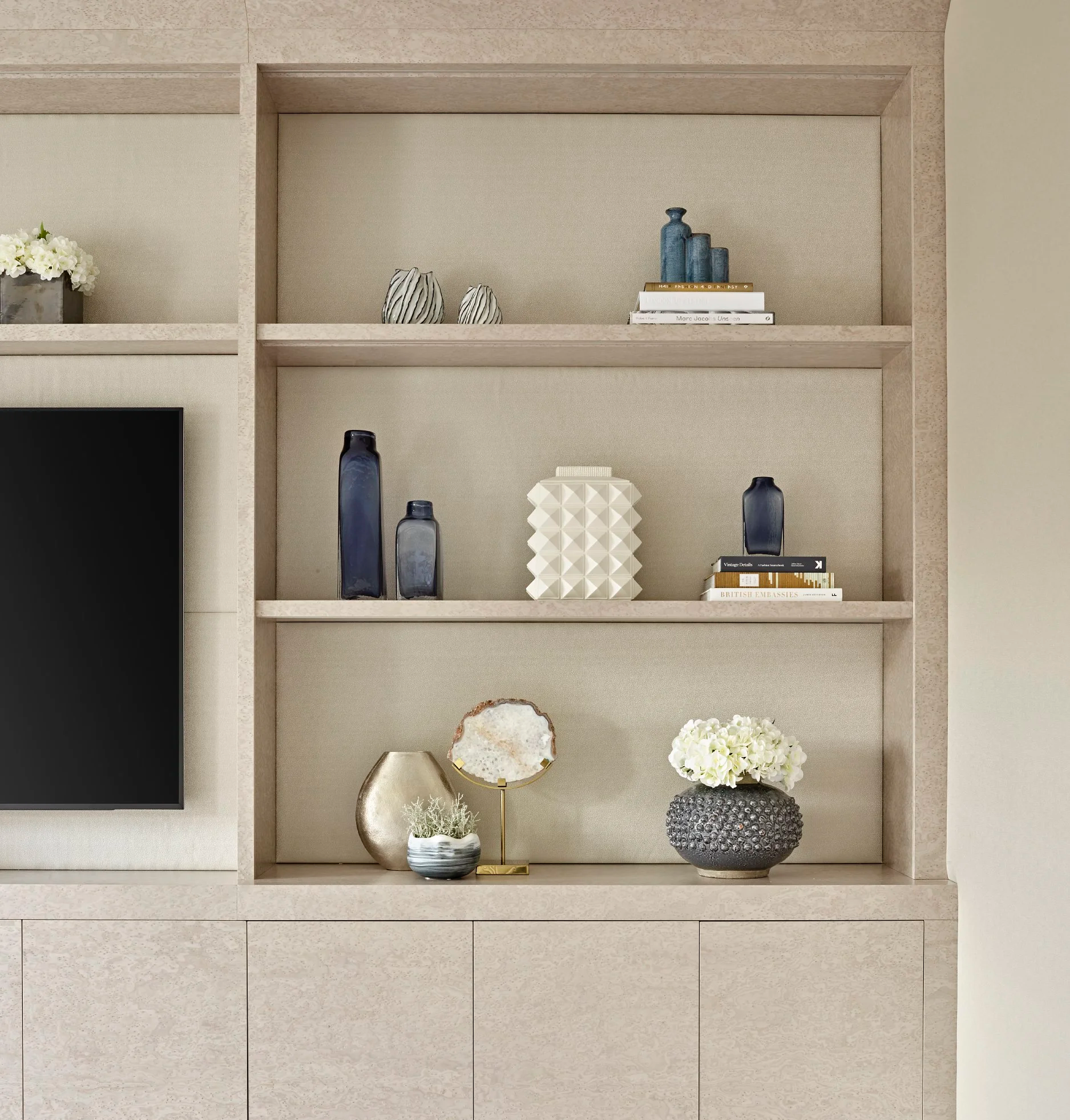 Luxury TV joinery with open shelves styled with vases, books, flowers, and decorative objects in a modern living room.